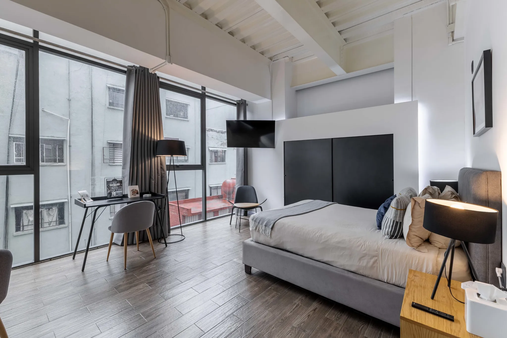 A stylish bedroom with a large window overlooking a building.