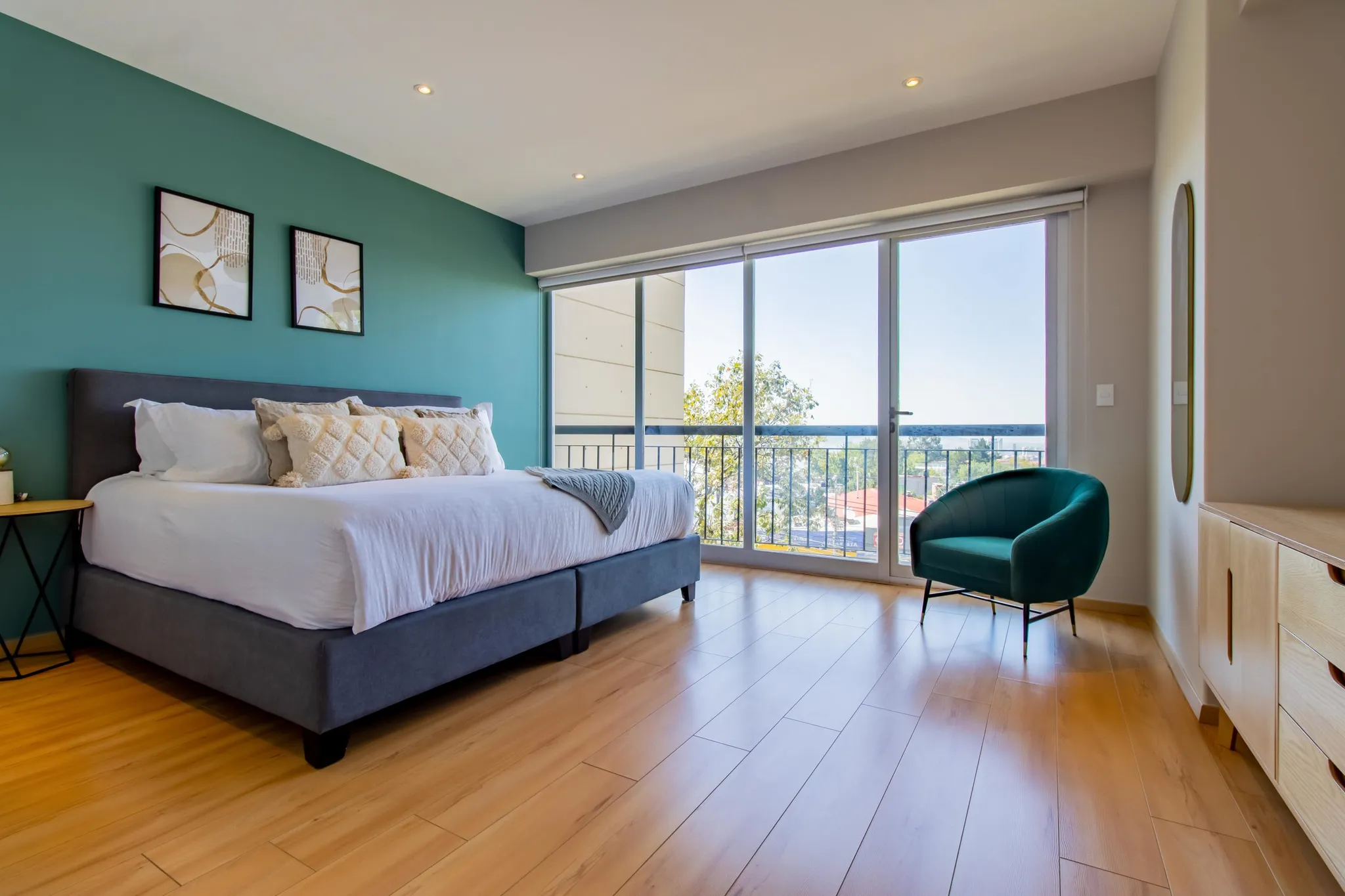 Bedroom with a king-size bed, green accent wall, and balcony doors.