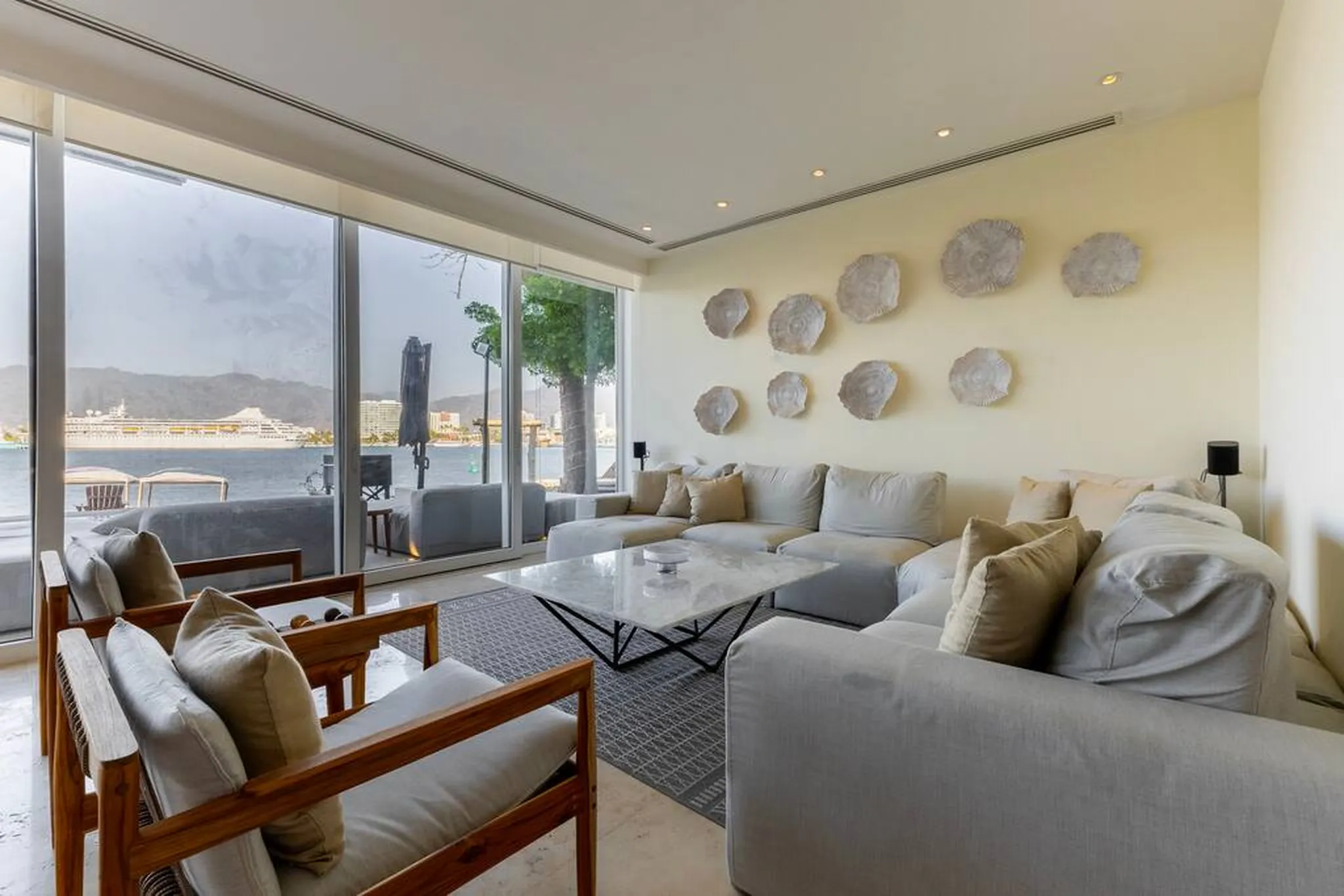 A living room with a large sectional sofa, armchairs, and a marble coffee table.