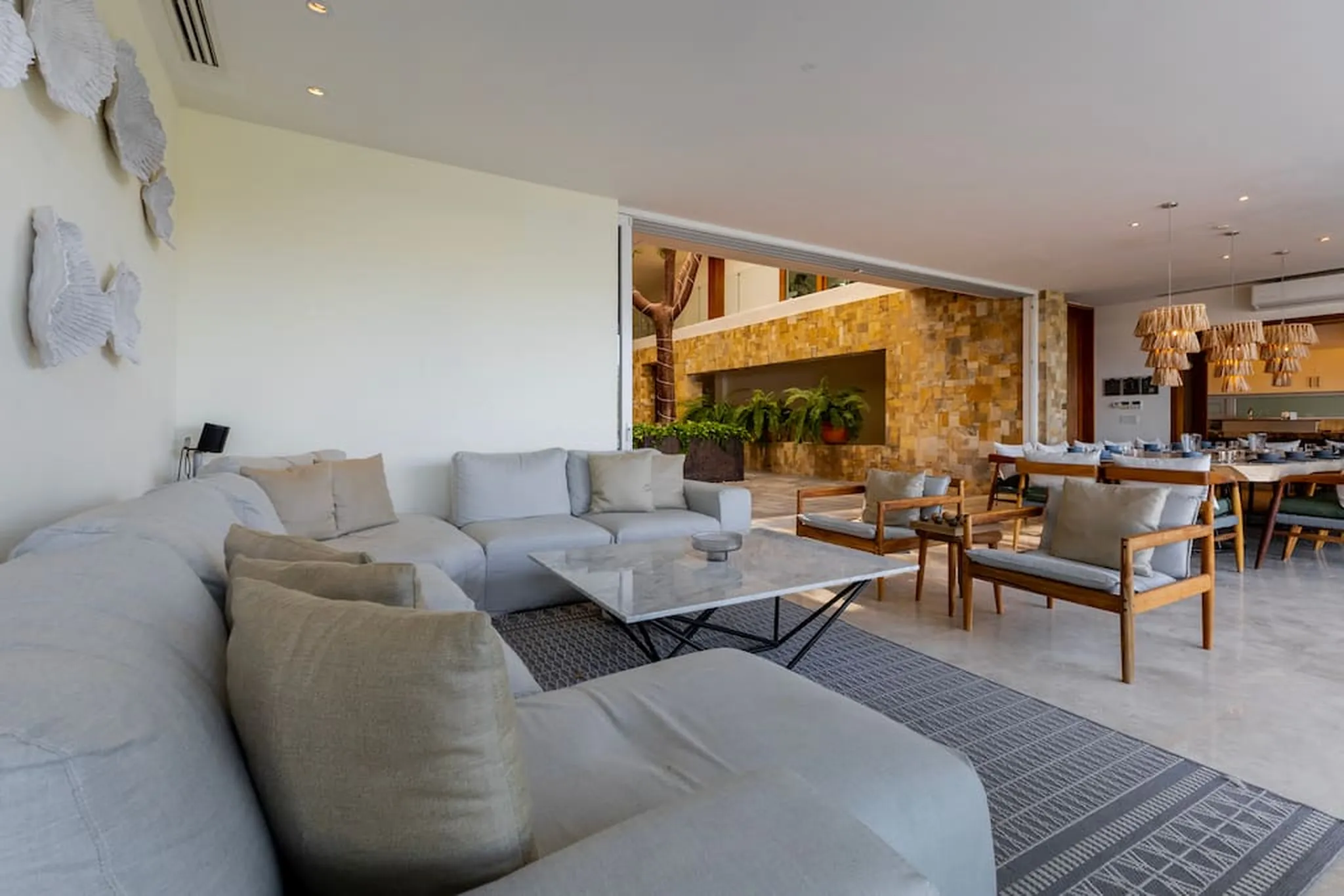 A light-filled living room with a sectional sofa and a dining area.