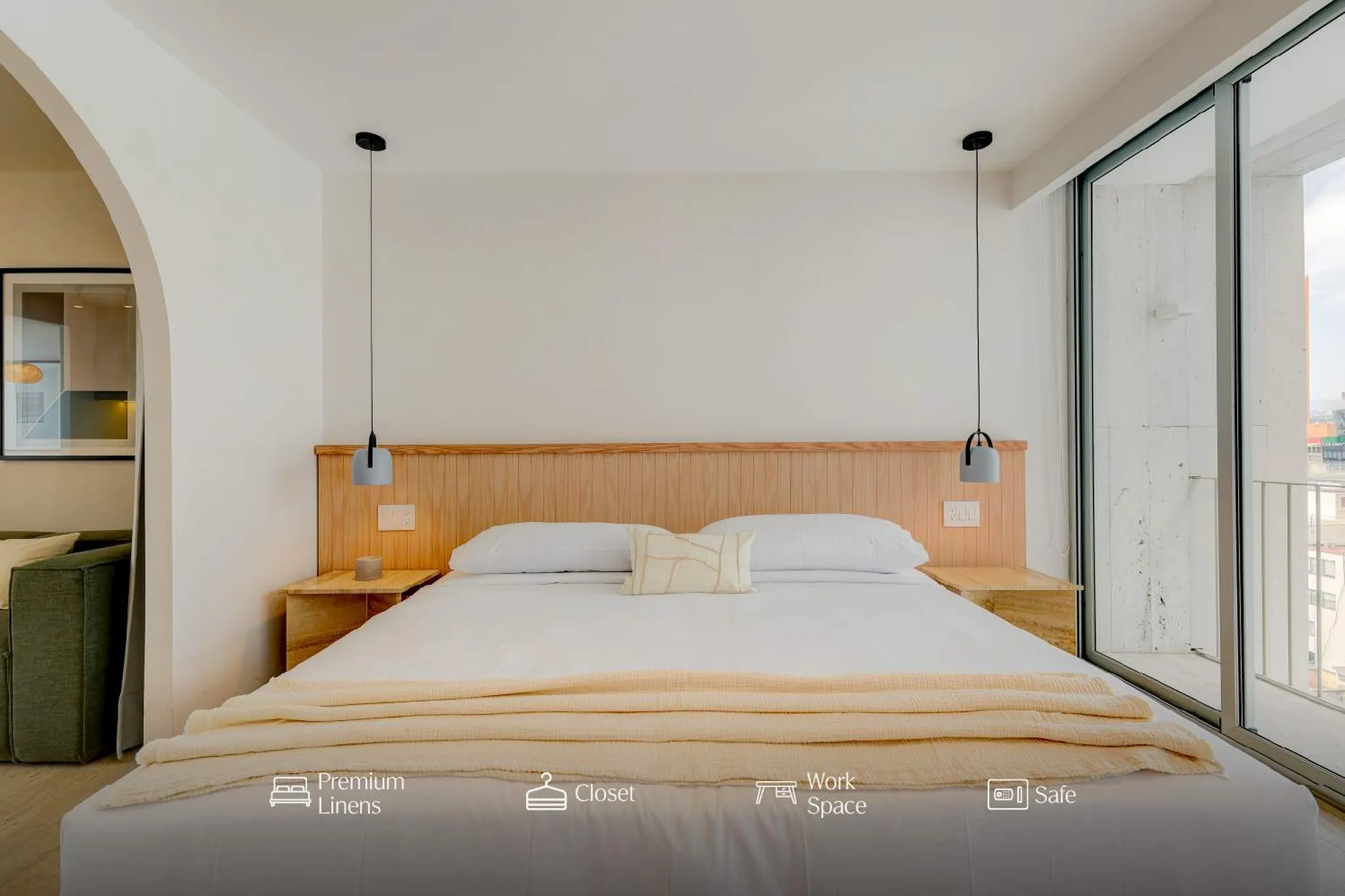 A modern bedroom with a large bed, wooden headboard, and a large window.