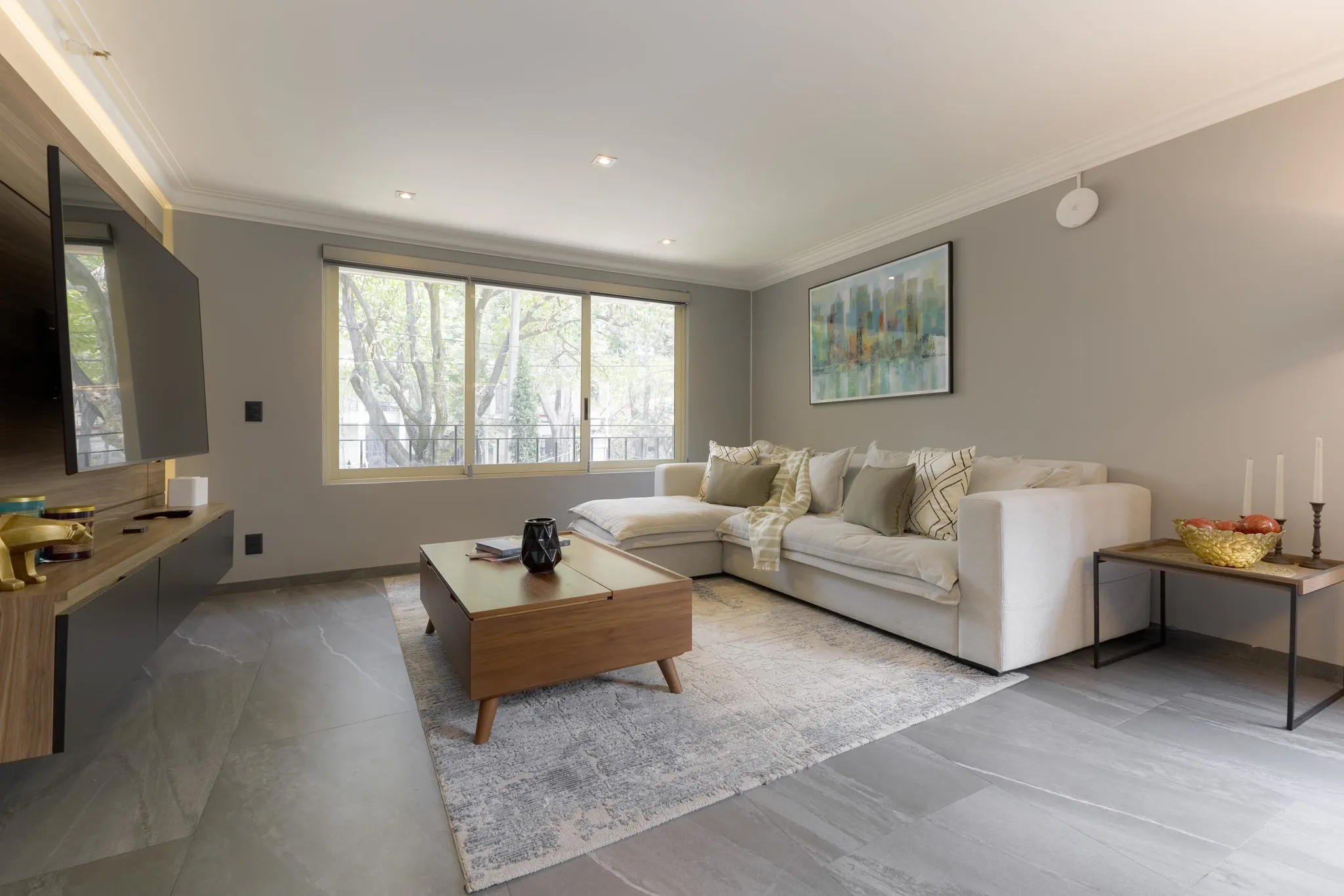 A modern living room features a large sectional sofa, a wooden coffee table, and a stylish abstract