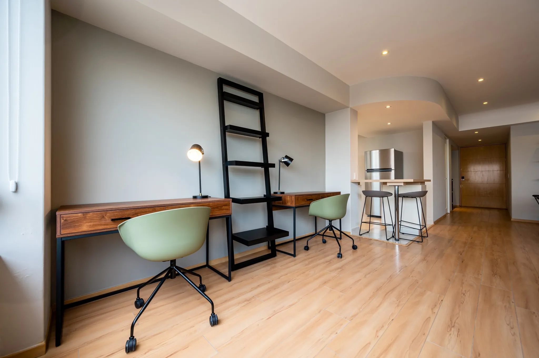 Two work desks with ergonomic chairs and a ladder shelf in a Santa Fe apartment.