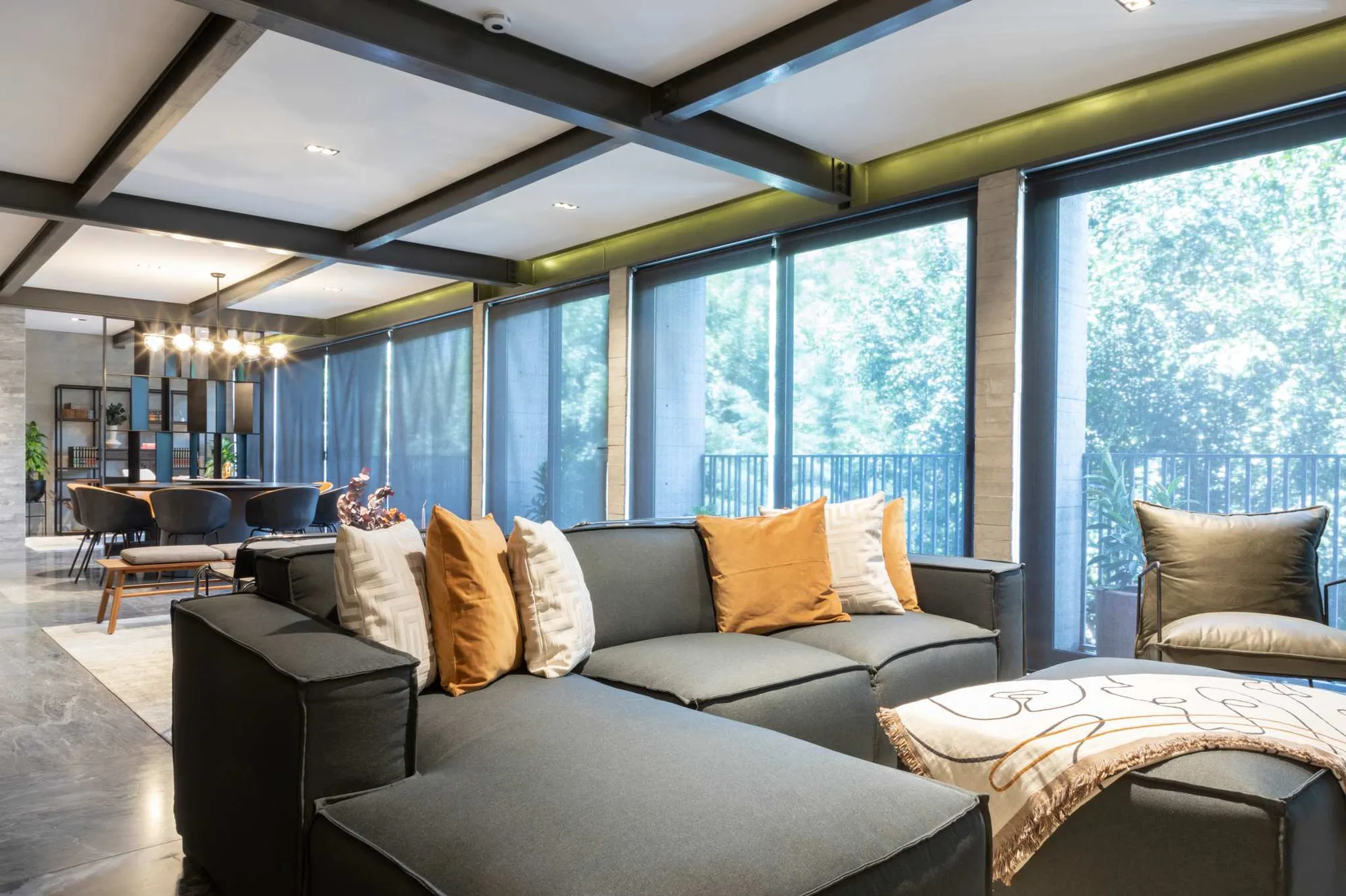 A sectional sofa with decorative pillows sits in a living room with large windows.