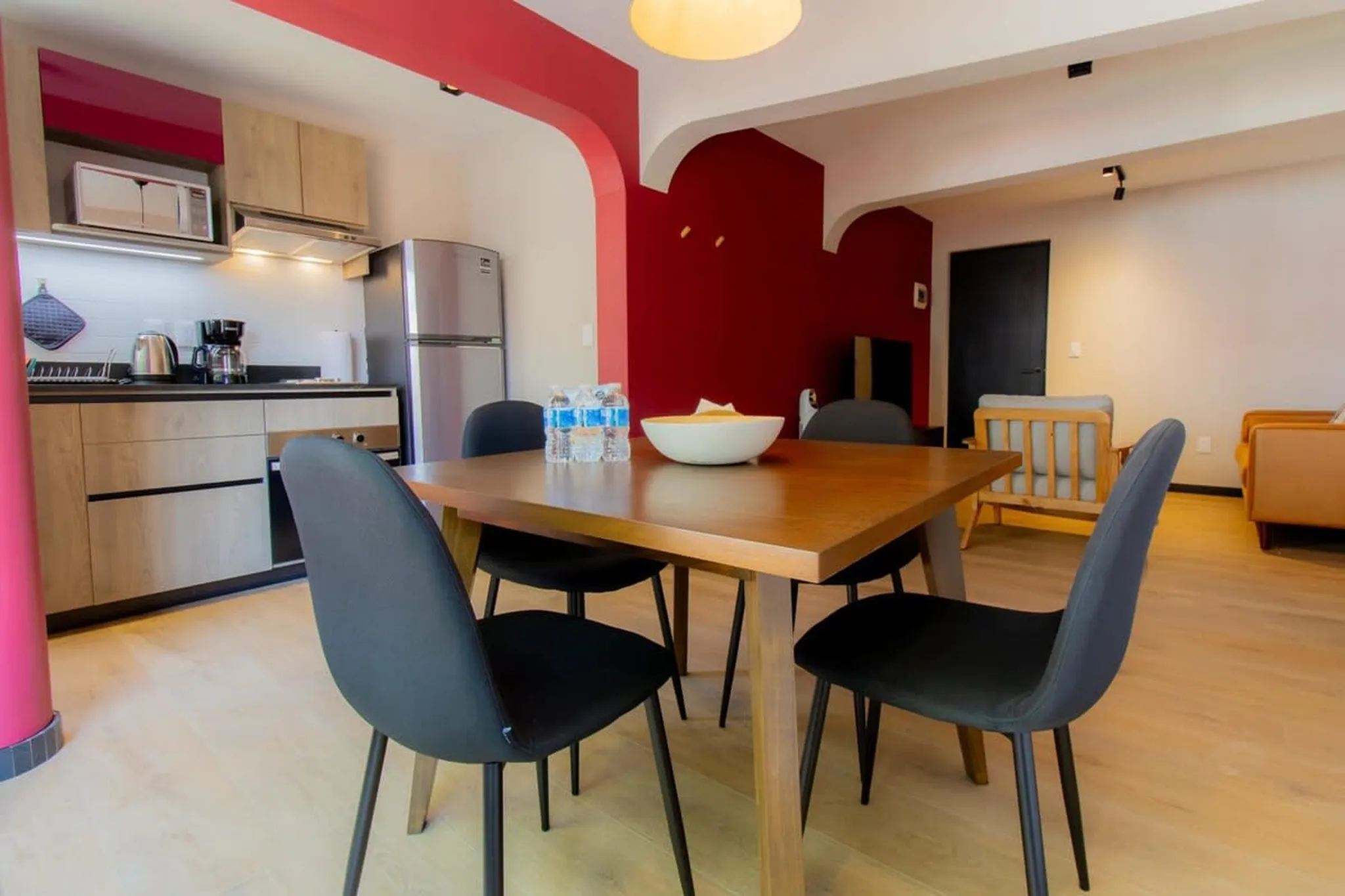 A dining table with four black chairs and bottles of water in the center.