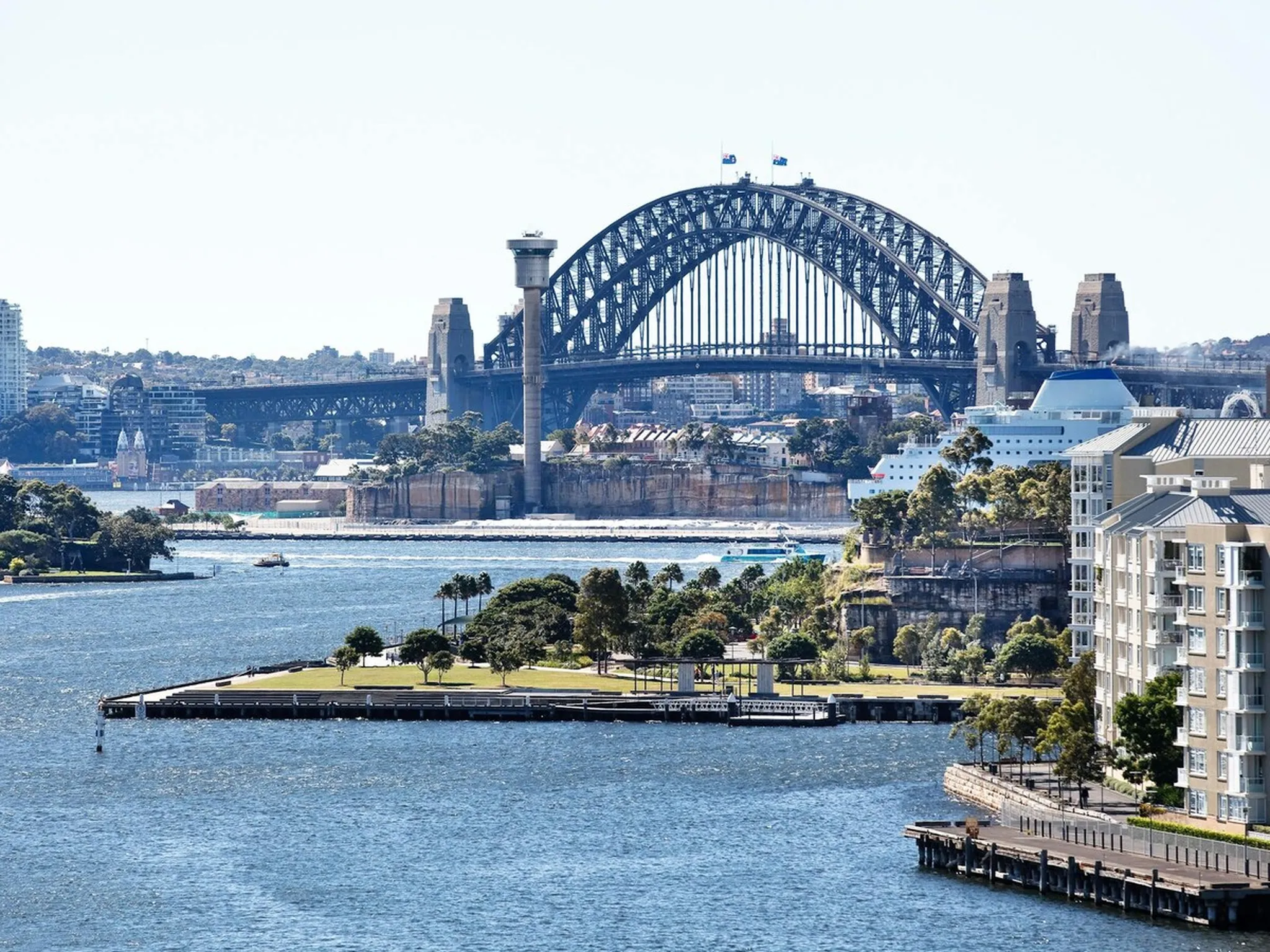 Sydney Harbour Bridge rising over Pirrama Park and the Pyrmont foreshore on a sunny day