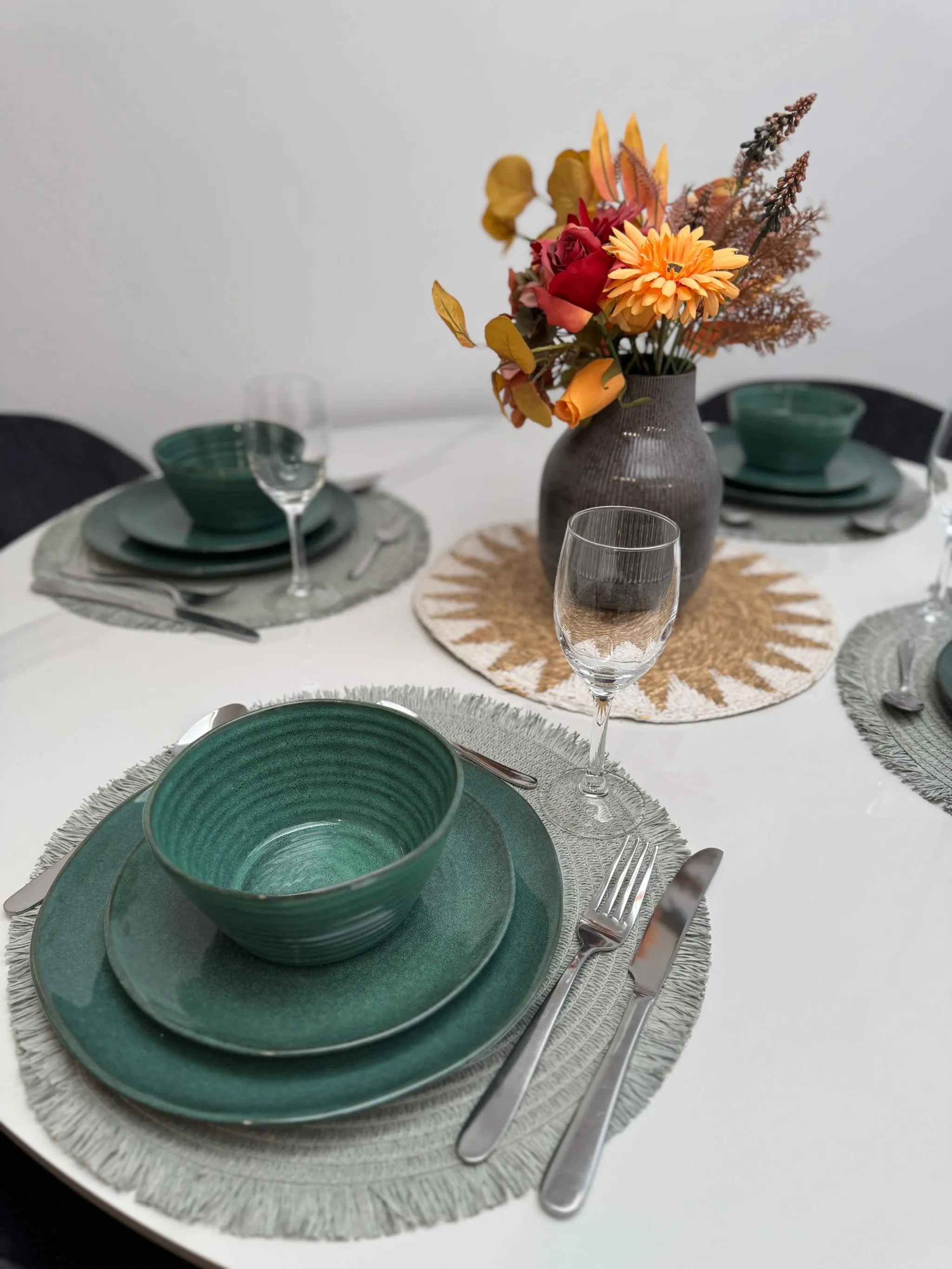 Table setting with green dishes and a vase of autumn flowers in the Harris St House
