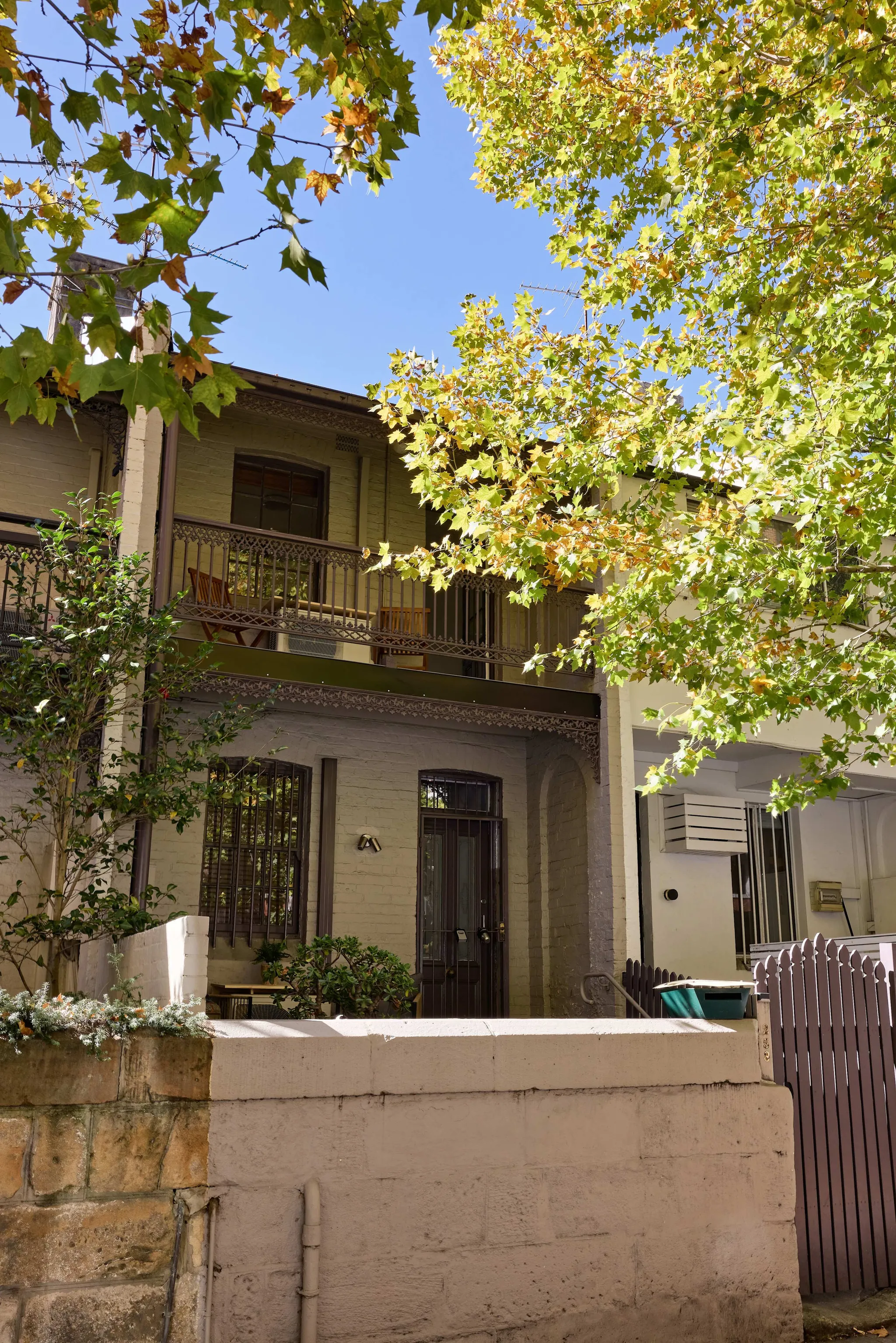 Two-storey brick Harris St House in Pyrmont with wrought-iron balconies and a street tree out front
