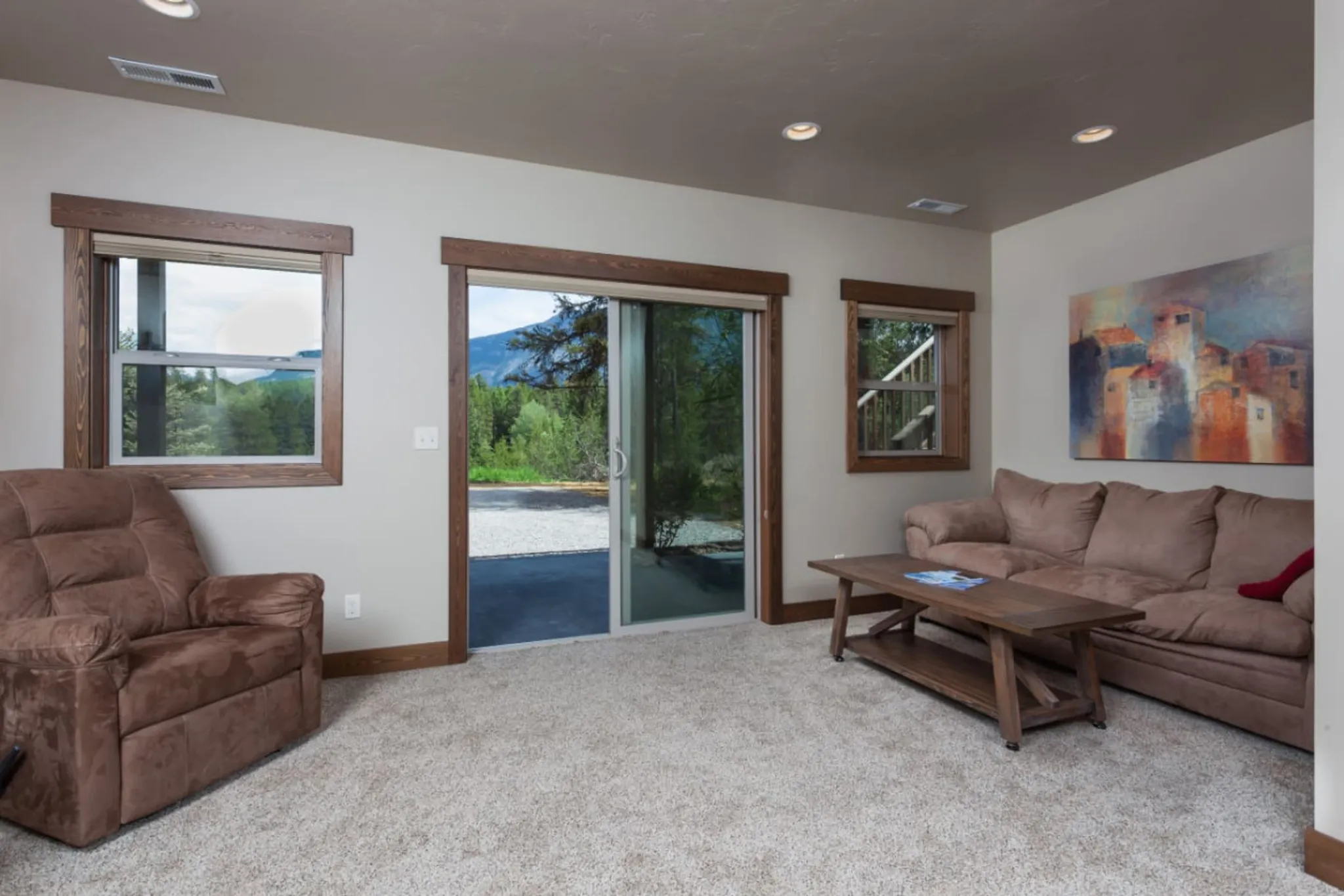 A living room with a brown recliner, a sofa, a coffee table, and a sliding glass door.