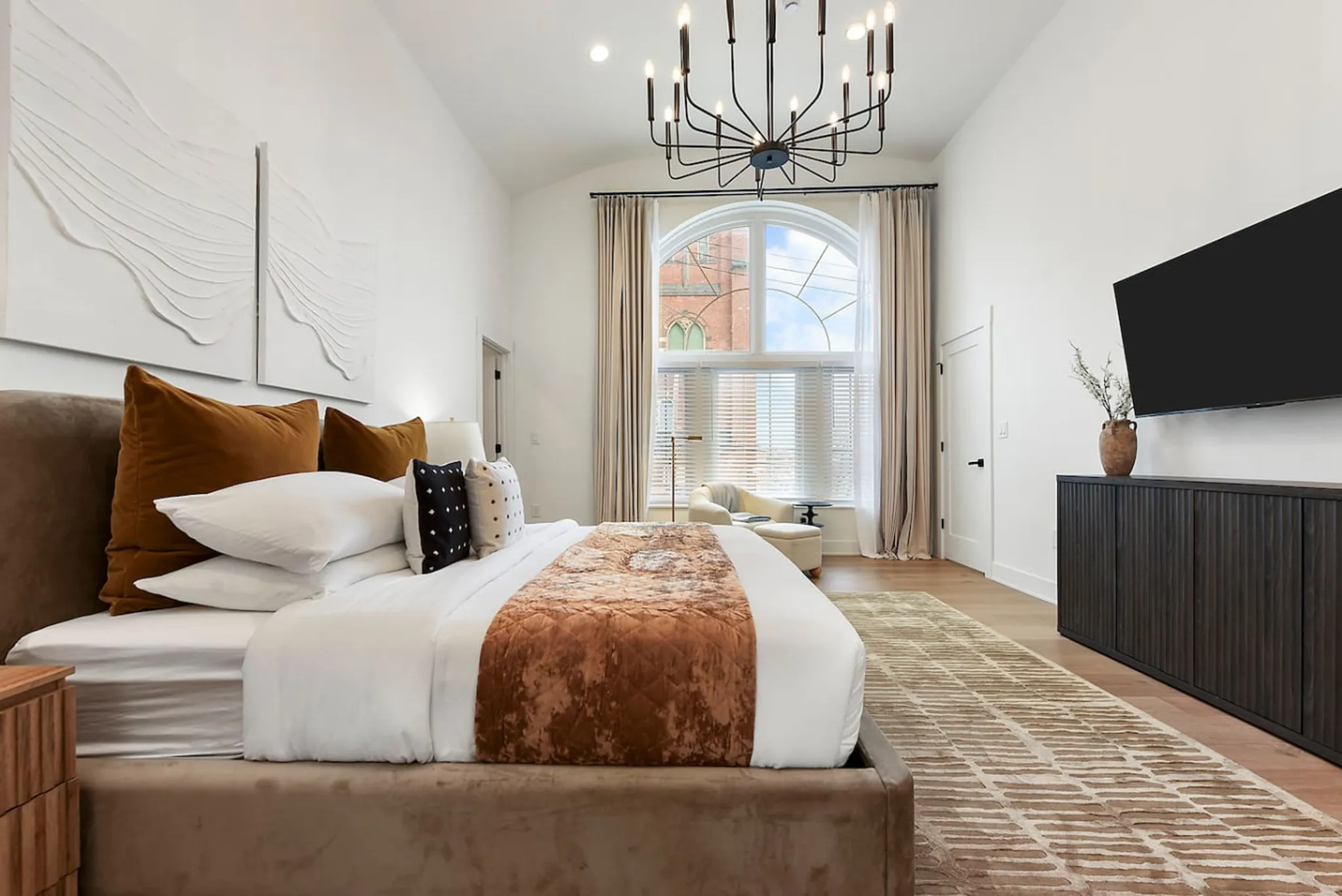 King bedroom with a chandelier and arched church window at the Converted Church Escape