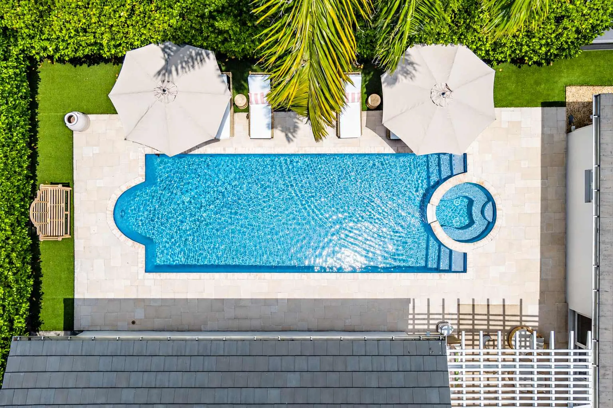 Aerial view of a Hotel Home Stays home in West Palm Beach: rectangular pool, spa and lounge chairs in a walled backyard