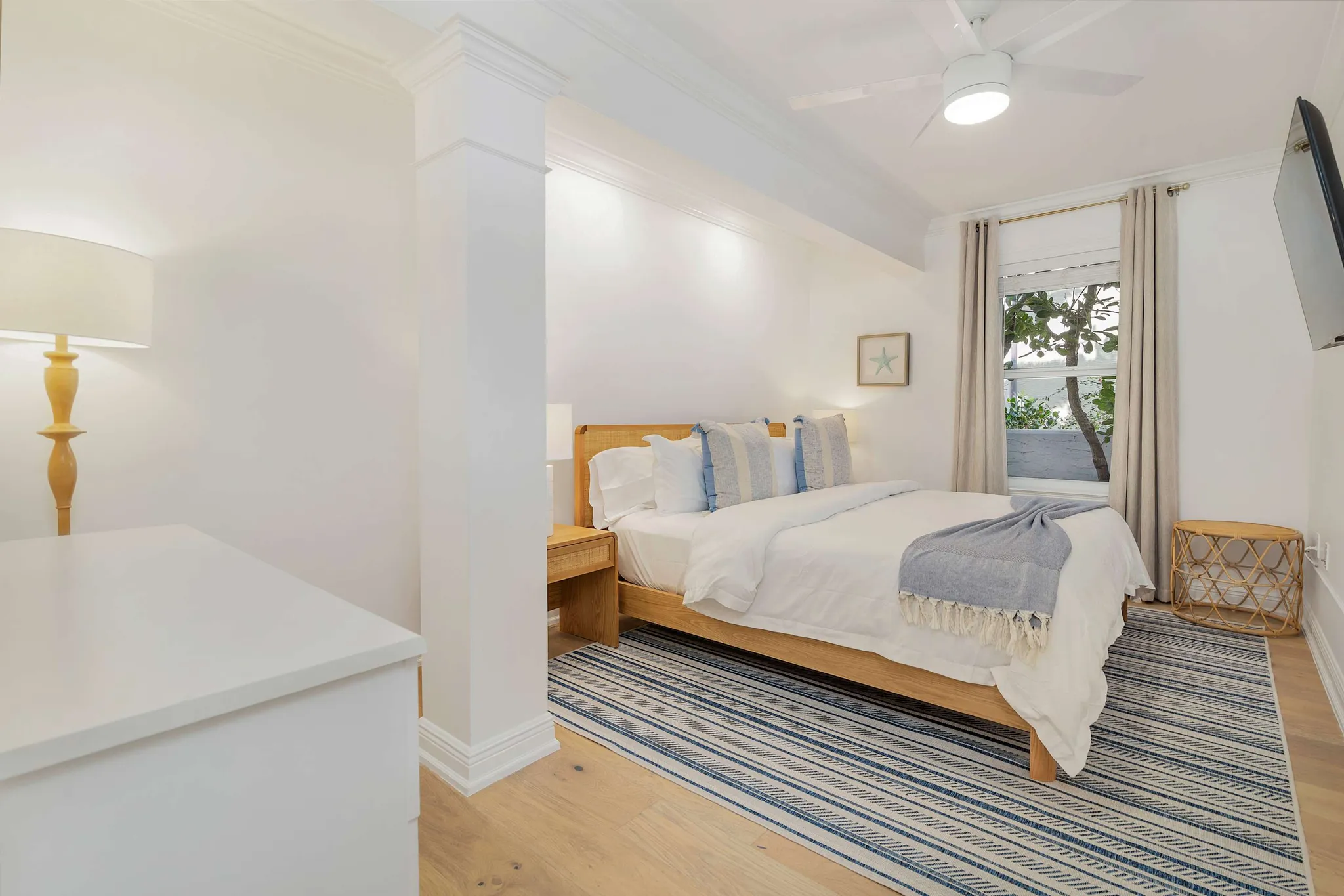 Stylish bedroom with a queen bed, layered white bedding, and bedside lamps