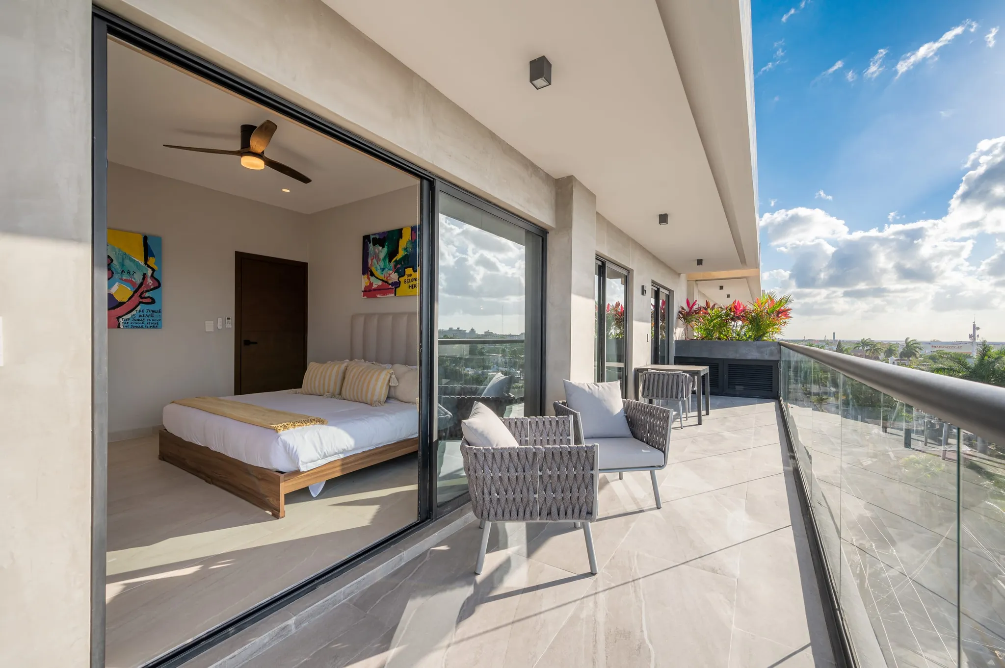 Bedroom opening onto a wide terrace with lounge chairs and a view over the town