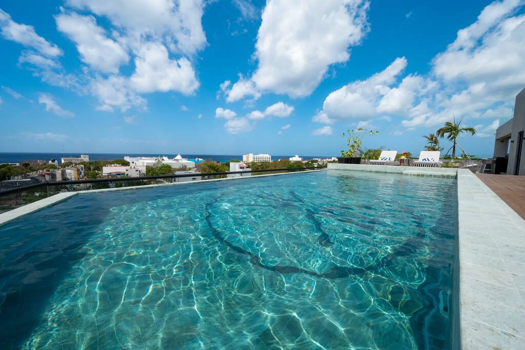 Rooftop infinity pool overlooking the rooftops of San Miguel de Cozumel and the sea under a blue sky
