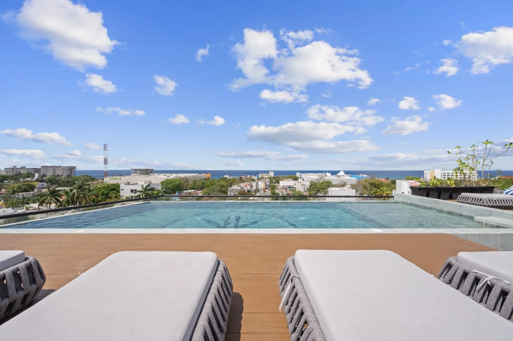Rooftop infinity pool with lounge chairs and a view toward the ocean