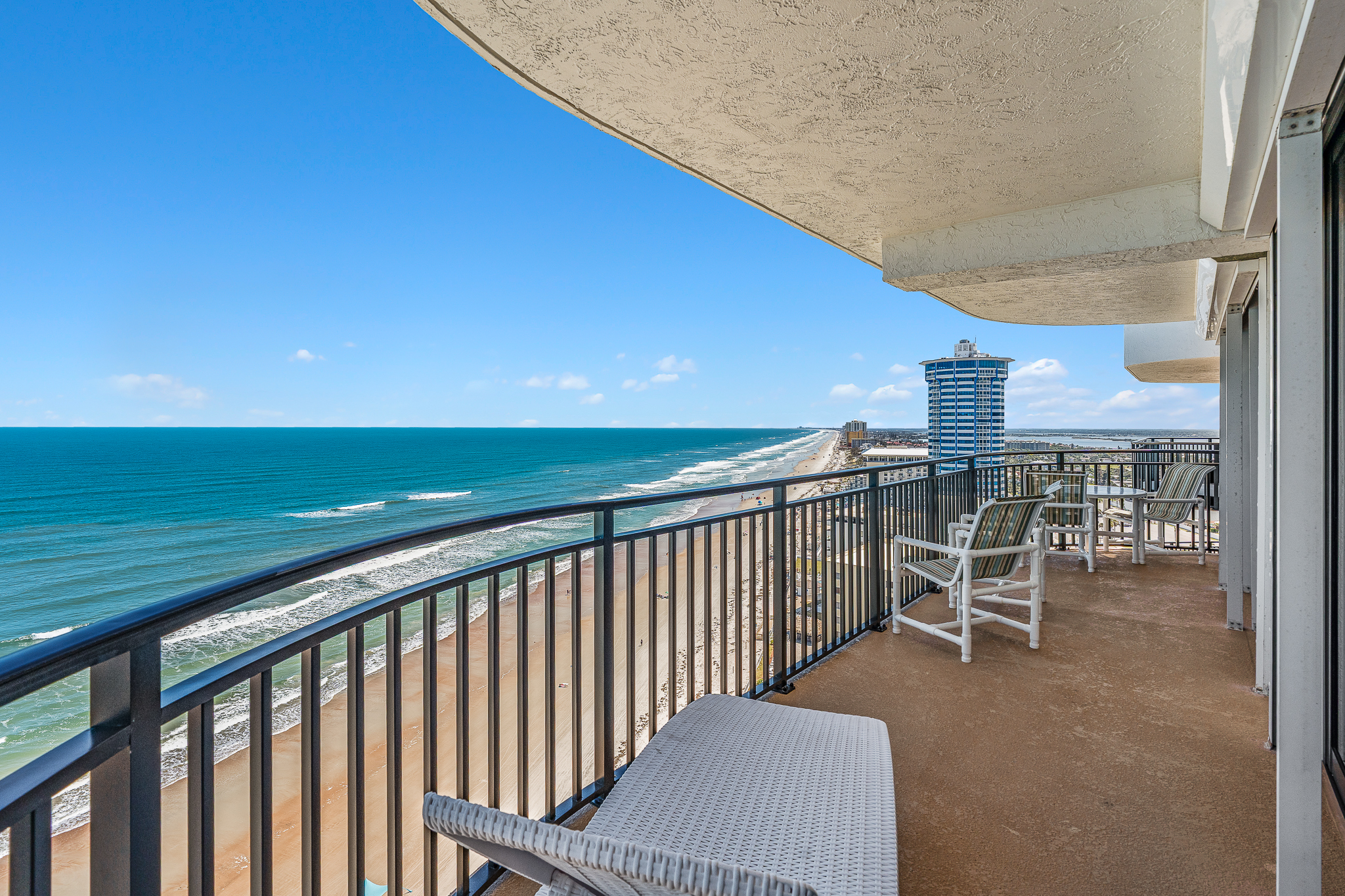 Oceanfront balcony with chairs overlooking a wide sandy beach and the blue Atlantic in Daytona Beach Shores