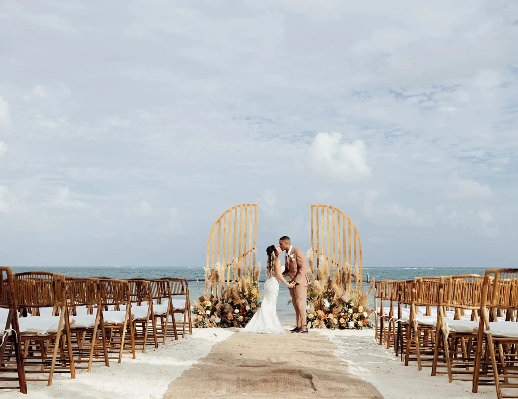 Bride and groom at a beachfront wedding ceremony in Riviera Maya with elegant floral decoration and ocean view at a luxury villa