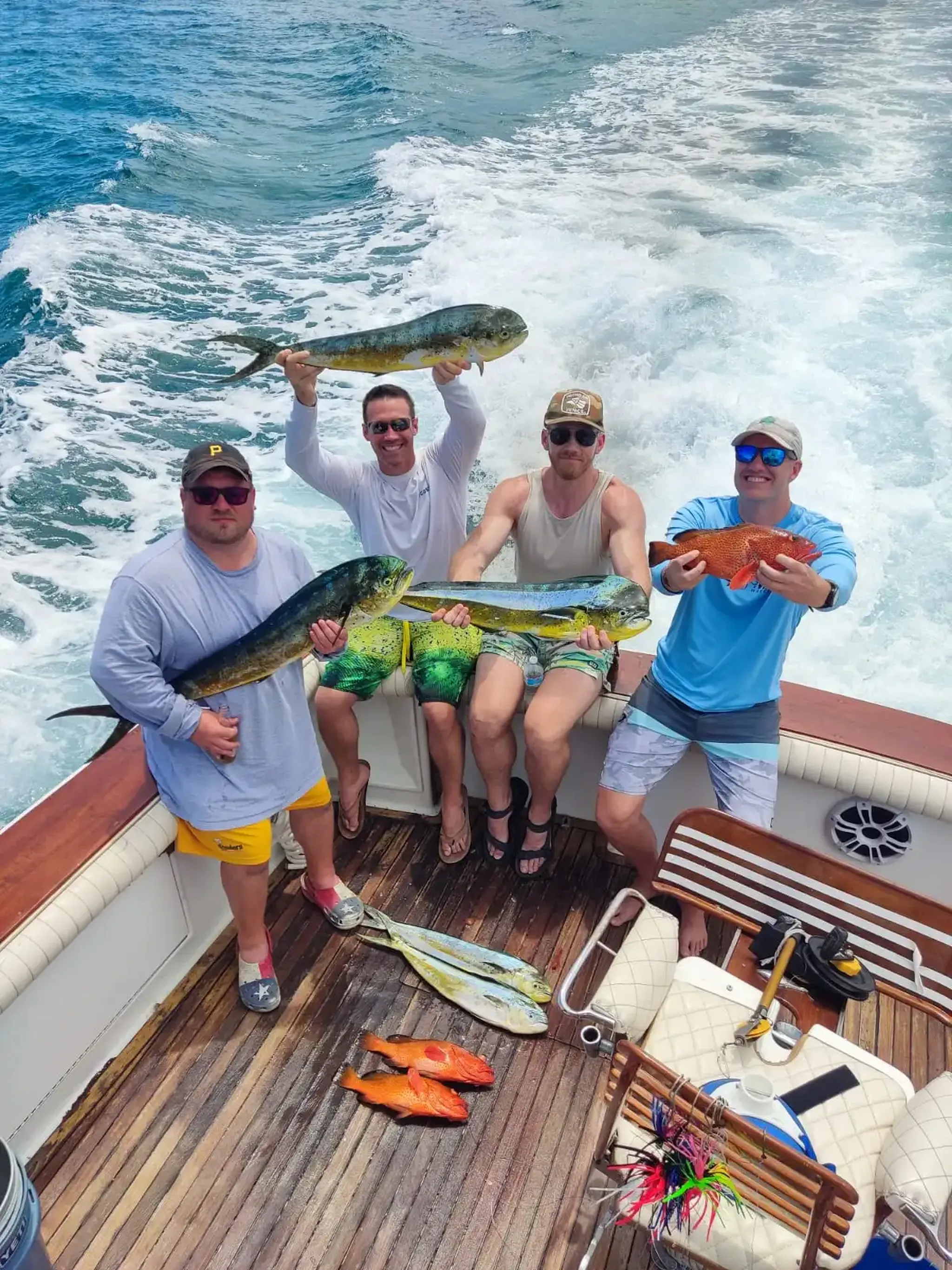 Group of friends on a luxury boat showing their fresh catch while enjoying a private fishing experience on the Caribbean Sea