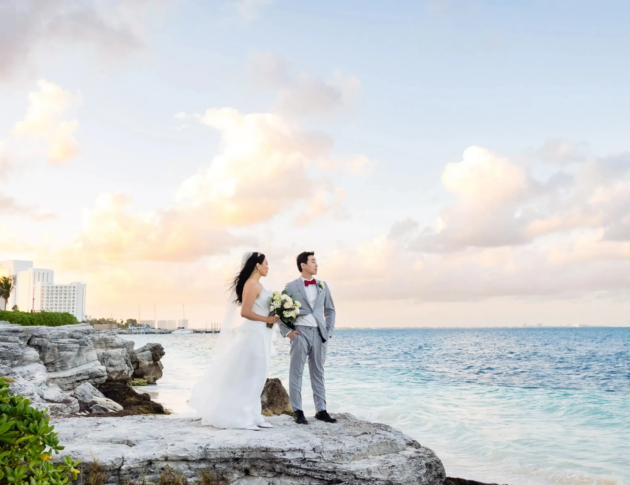 Bride and groom photoshot at coastline overlooking the ocean at sunset during a luxury villa wedding in Riviera Maya