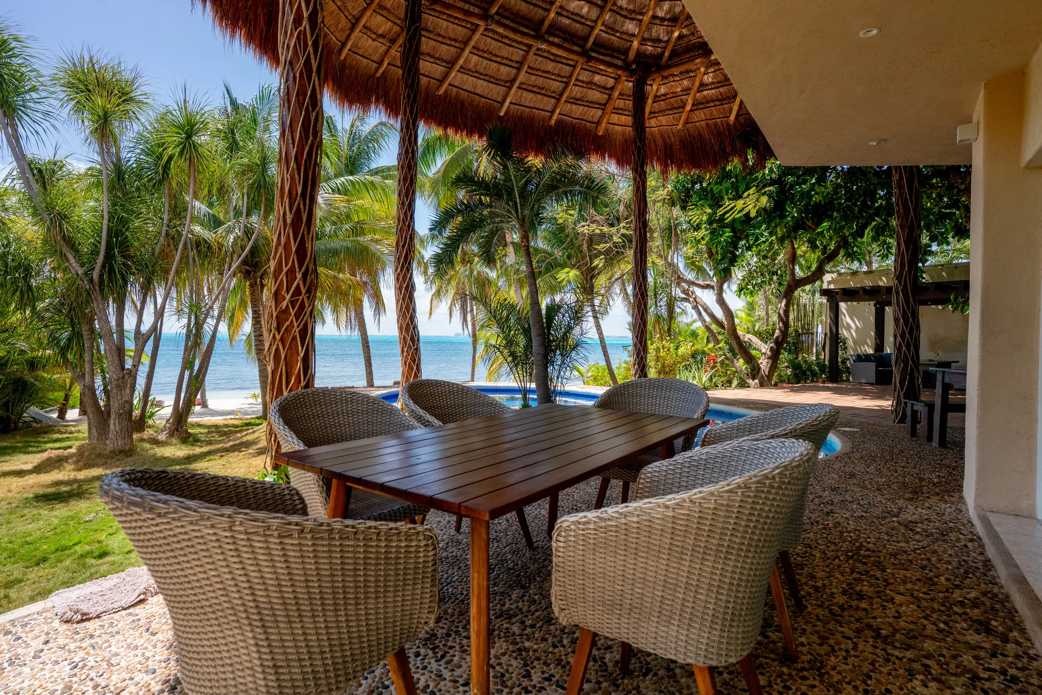 Outdoor seating area at an Isla Mujeres beachfront villa featuring ocean views, tropical surroundings and gathering.