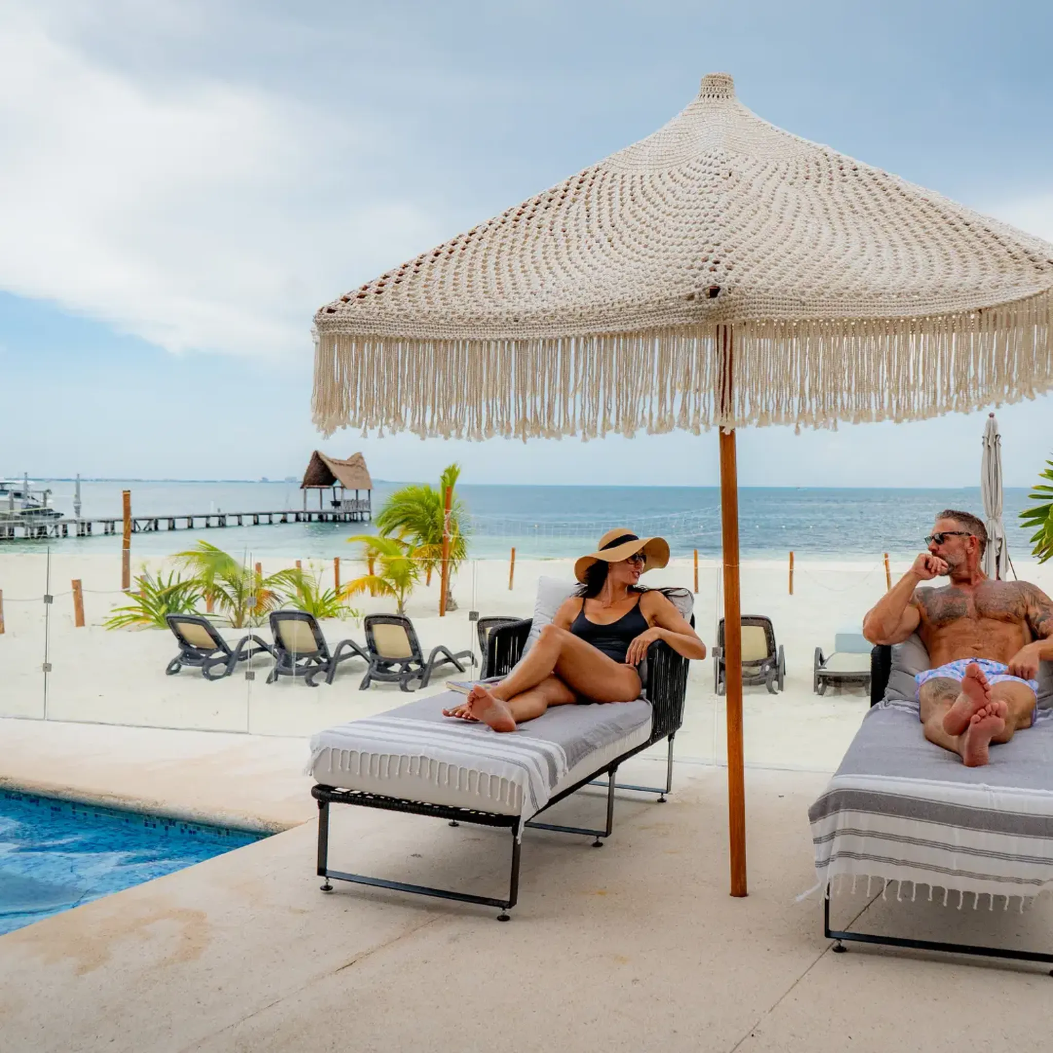 Couple relaxing on sun loungers in a pool at a beachfront luxury villa in Riviera Maya