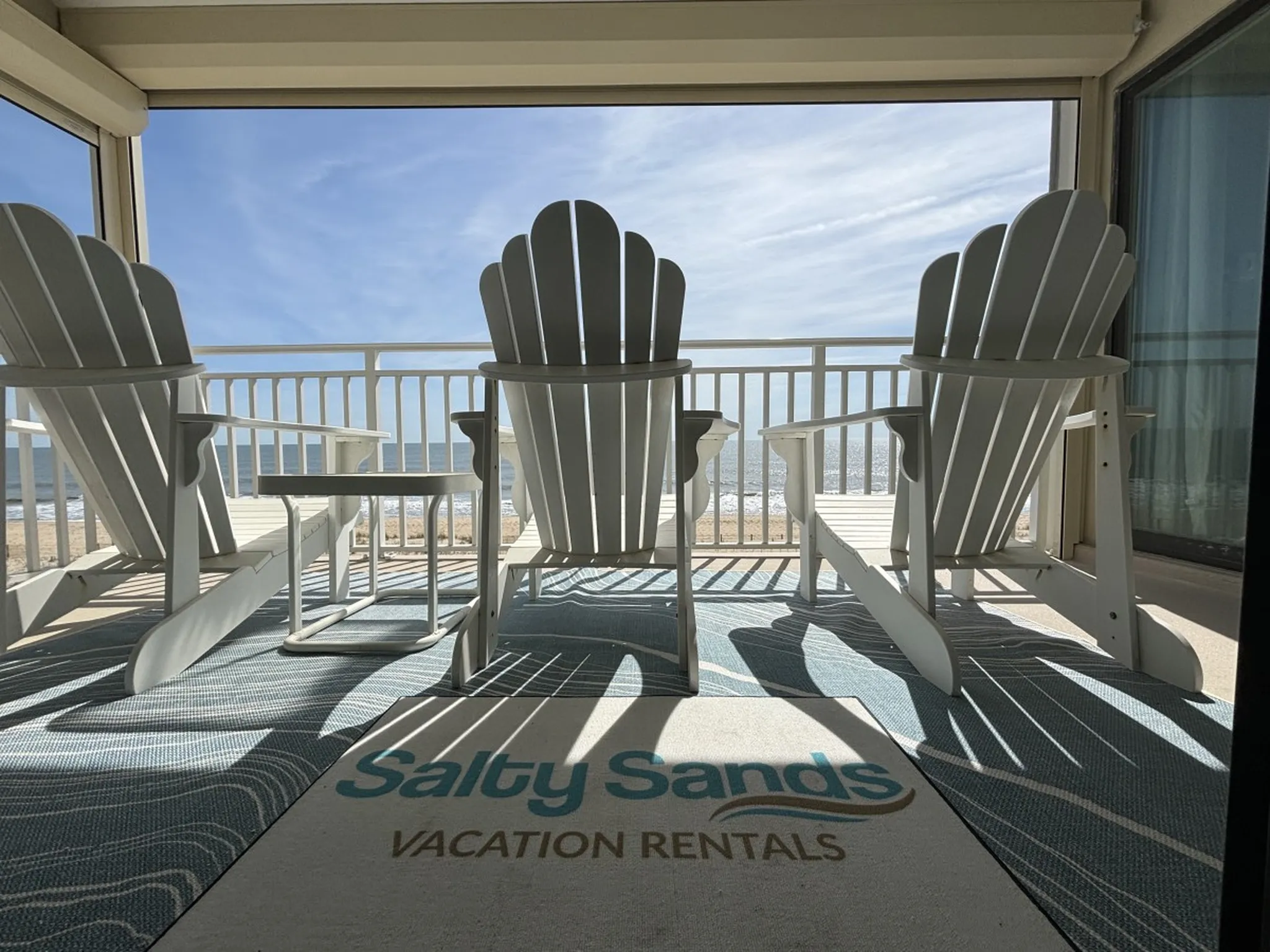 The oceanfront deck at Salty Sands with white Adirondack chairs facing the Atlantic