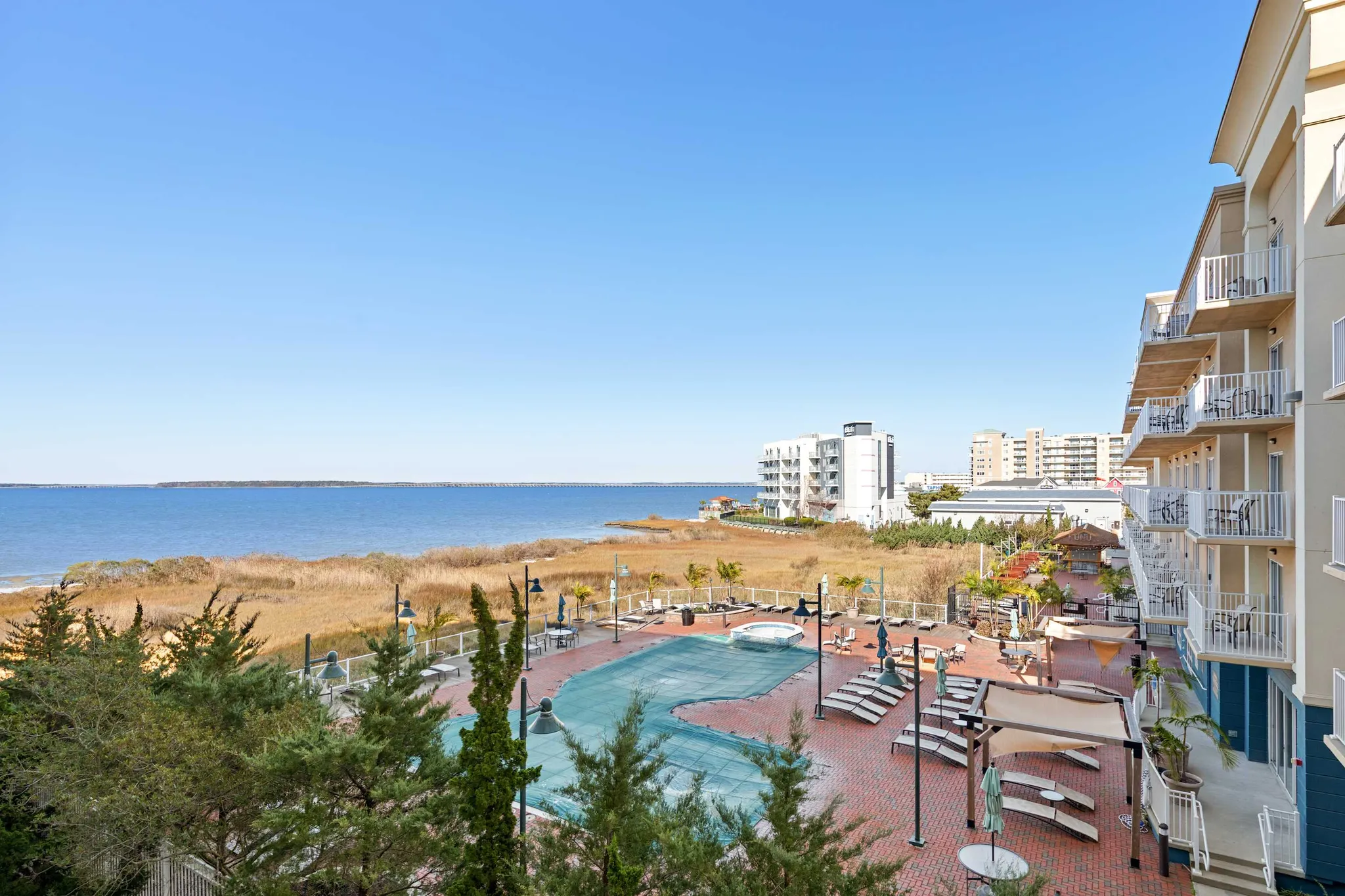 View from a Makai balcony over the bayfront pool deck and Isle of Wight Bay