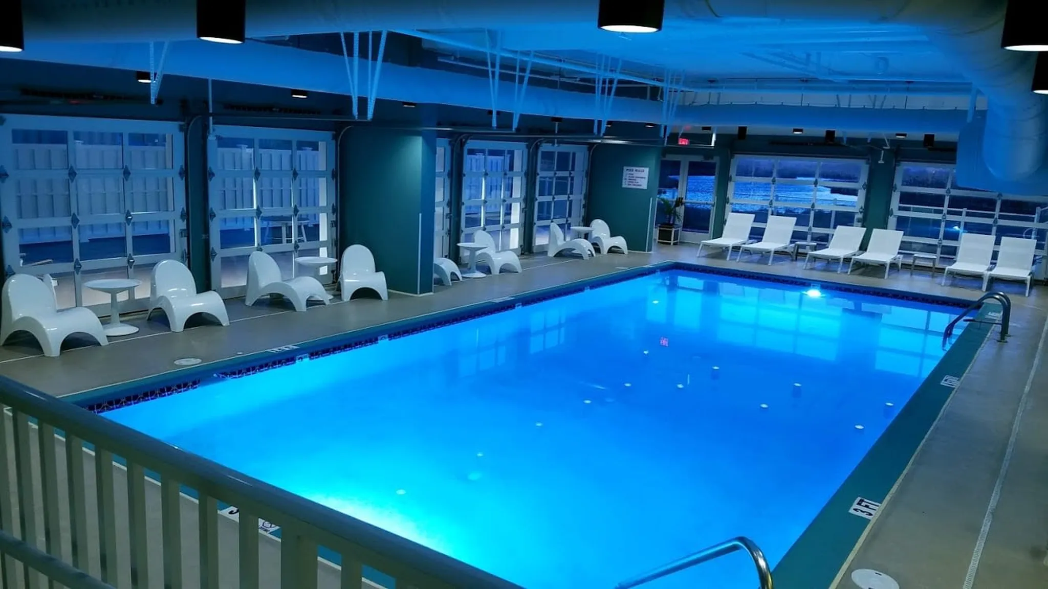 Indoor pool with blue water and lounge chairs.