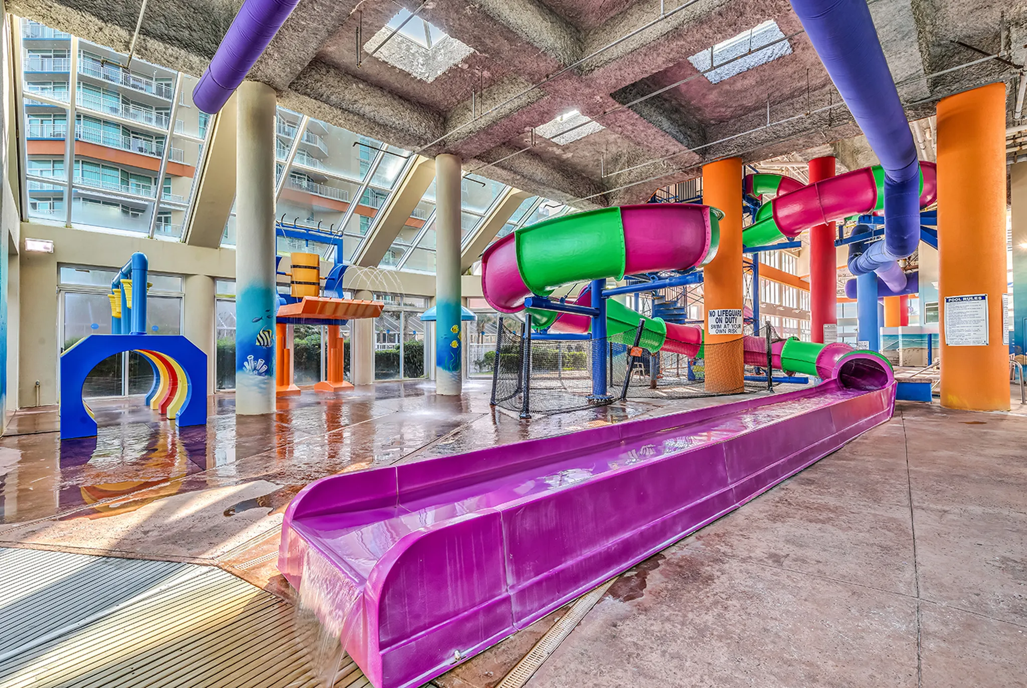 Indoor water park at Dunes Village with a large enclosed slide winding above the pool deck