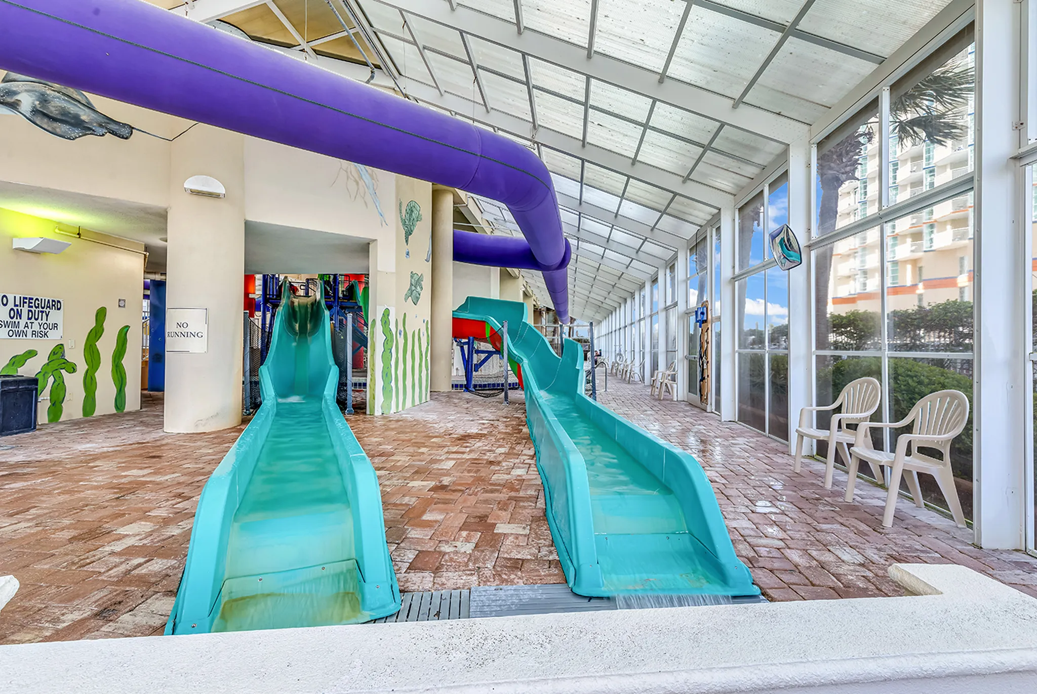 Twin turquoise waterslides running down into the indoor pool at Dunes Village