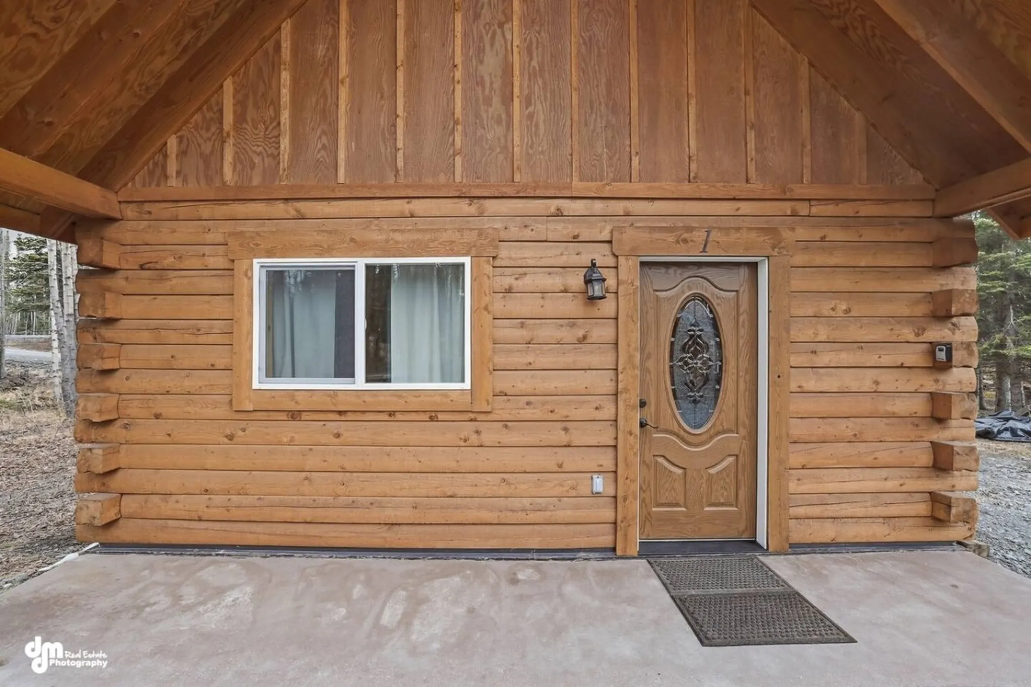 Log cabin exterior with a wooden door, a window, and a covered porch.