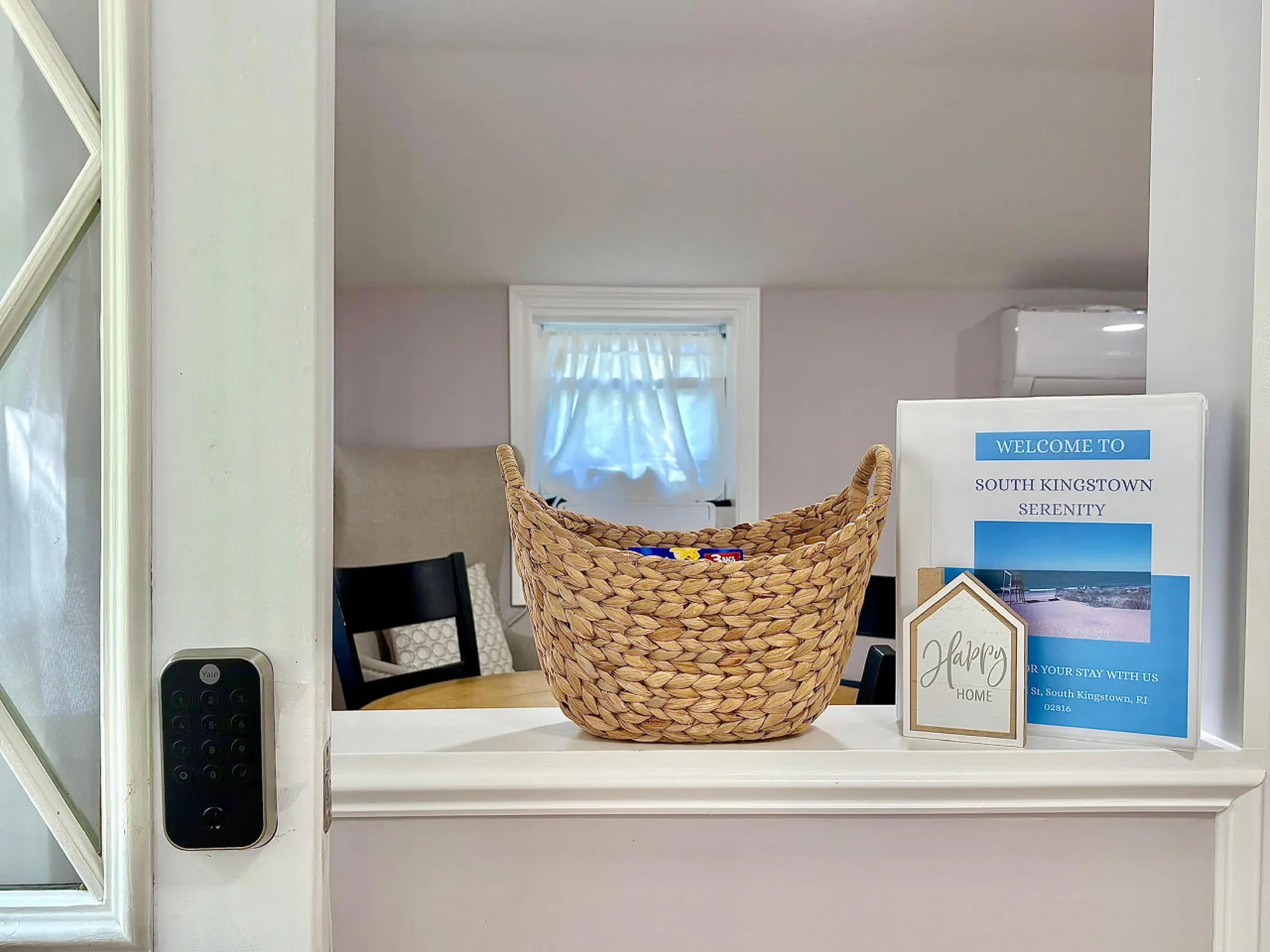A welcome binder and basket of snacks sit on a ledge. A digital lock is on the left.