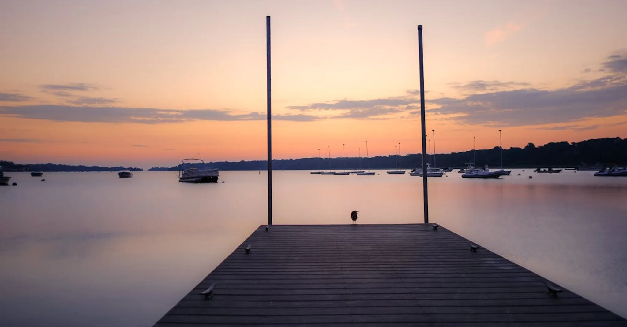 Wooden dock at sunset over a calm harbor