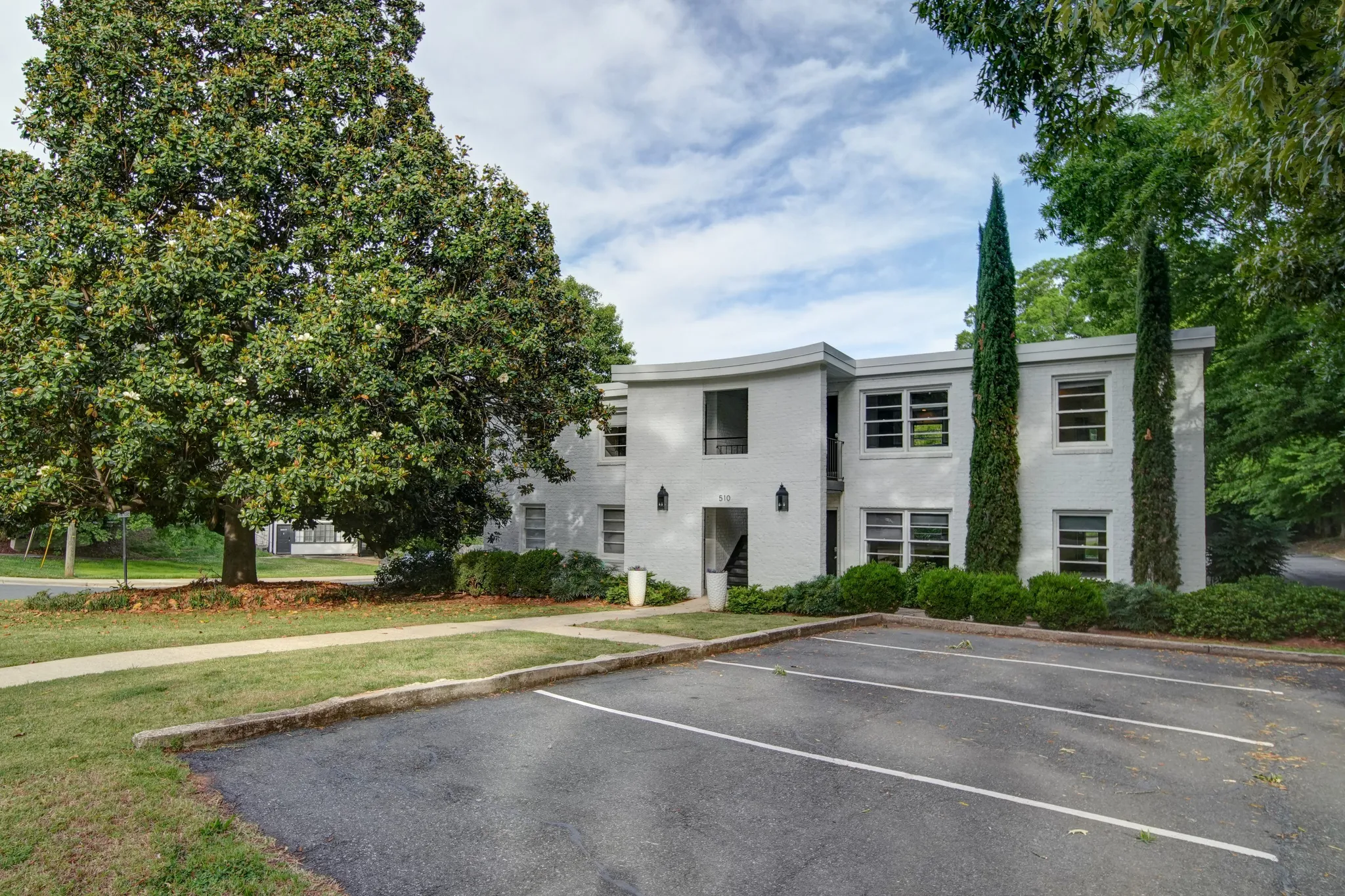Corner of a red brick building with tall windows and a Parking for Tenants Only sign beside a paved driveway