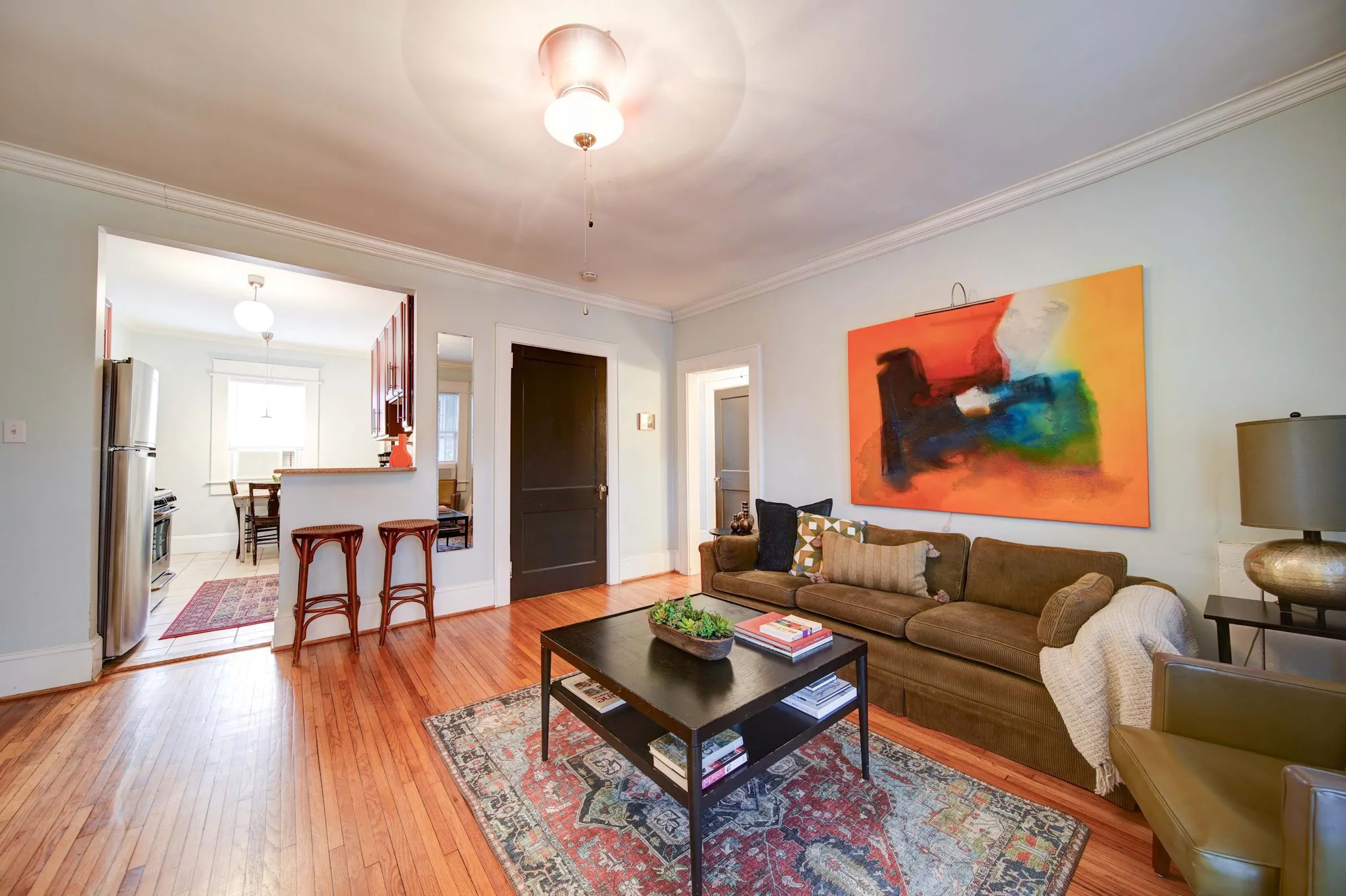 Living room with original hardwood floors, a brown sofa, and a large orange abstract painting