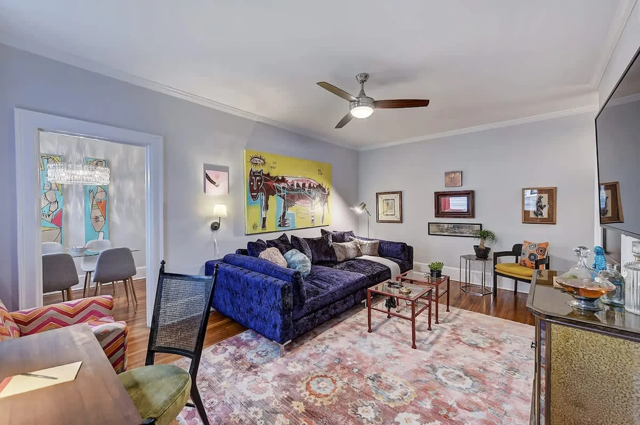 Living room with a blue sectional sofa, colorful rug, and abstract wall art