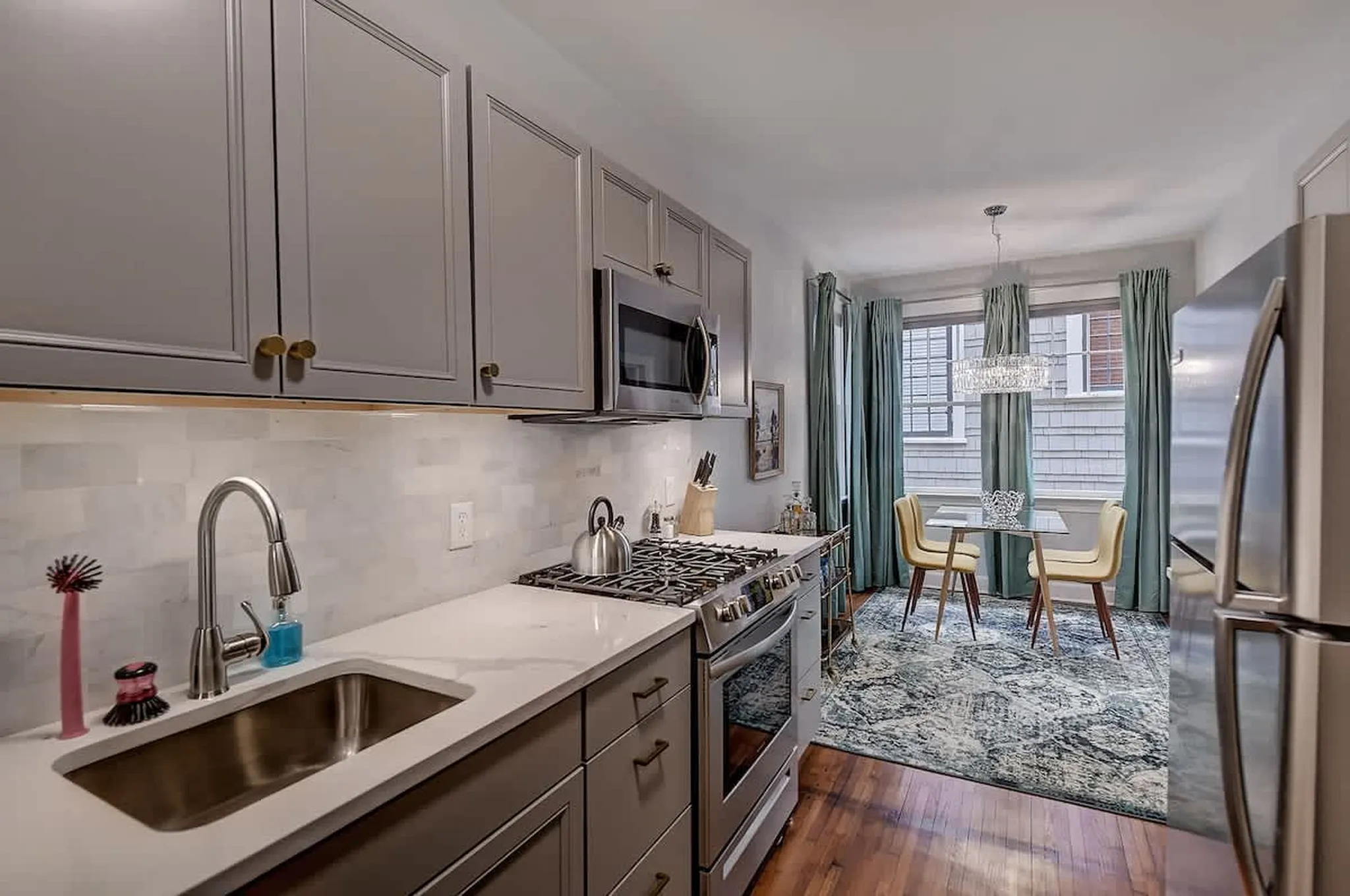 Modern kitchen with gray cabinets, a stainless gas stove, and a dining area