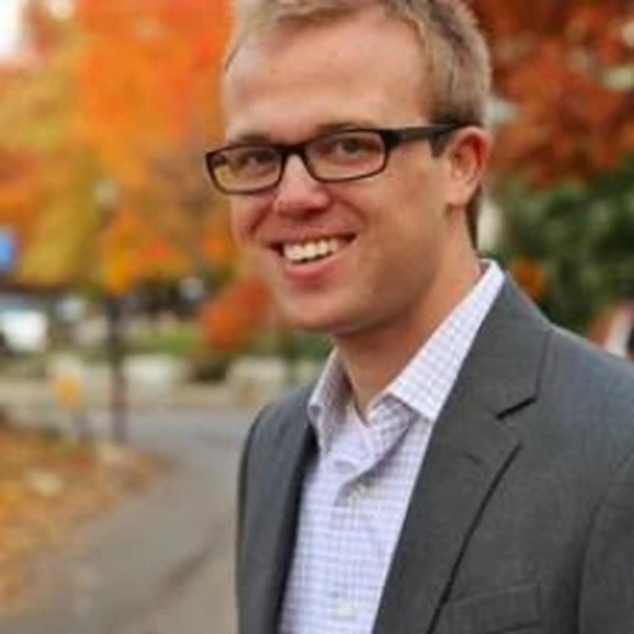 Ben's headshot, smiling with grey jacket