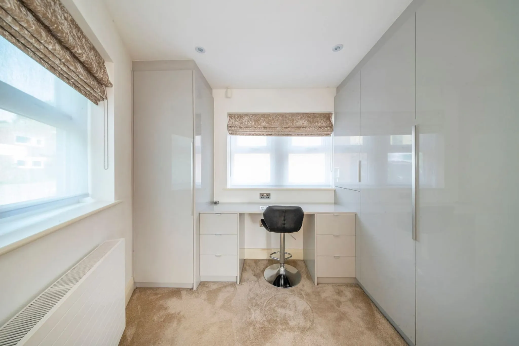 A modern office with a white desk, grey chair, and built-in storage.