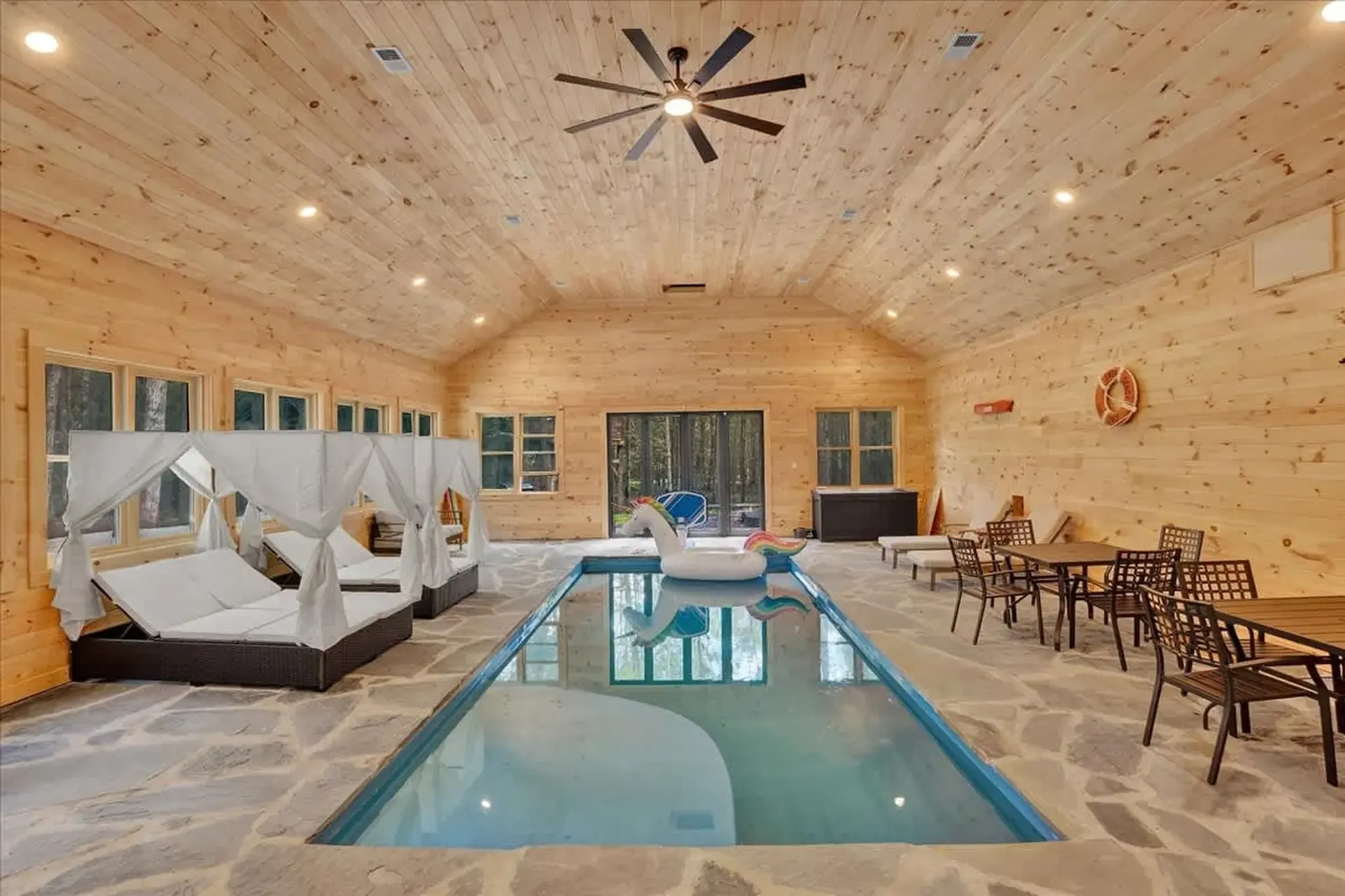 Large indoor swimming pool with lounge chairs at a luxury Poconos vacation rental