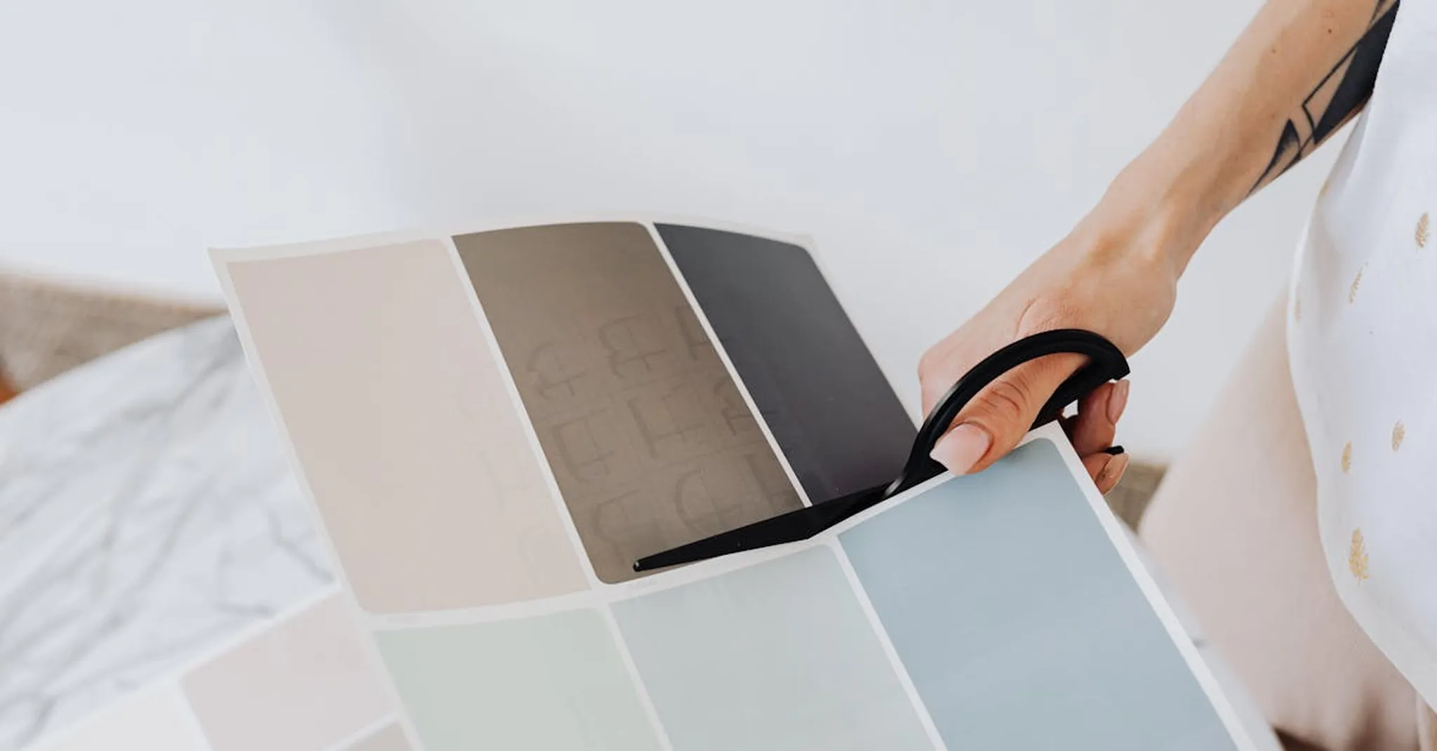 Close-up of a designer hand cutting paint sample cards for interior design.