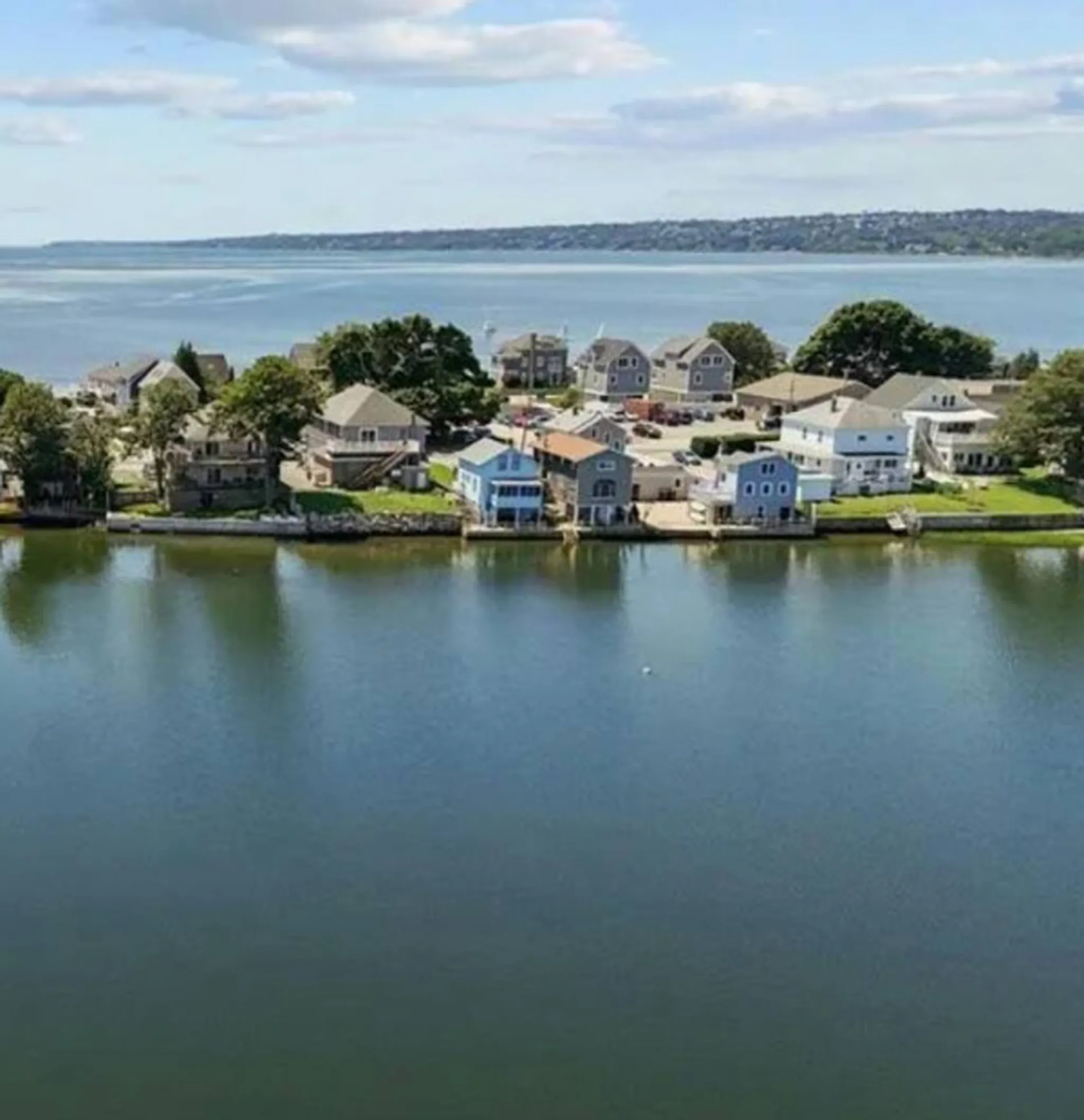 An aerial view of a coastal building with a rocky shoreline in the background.