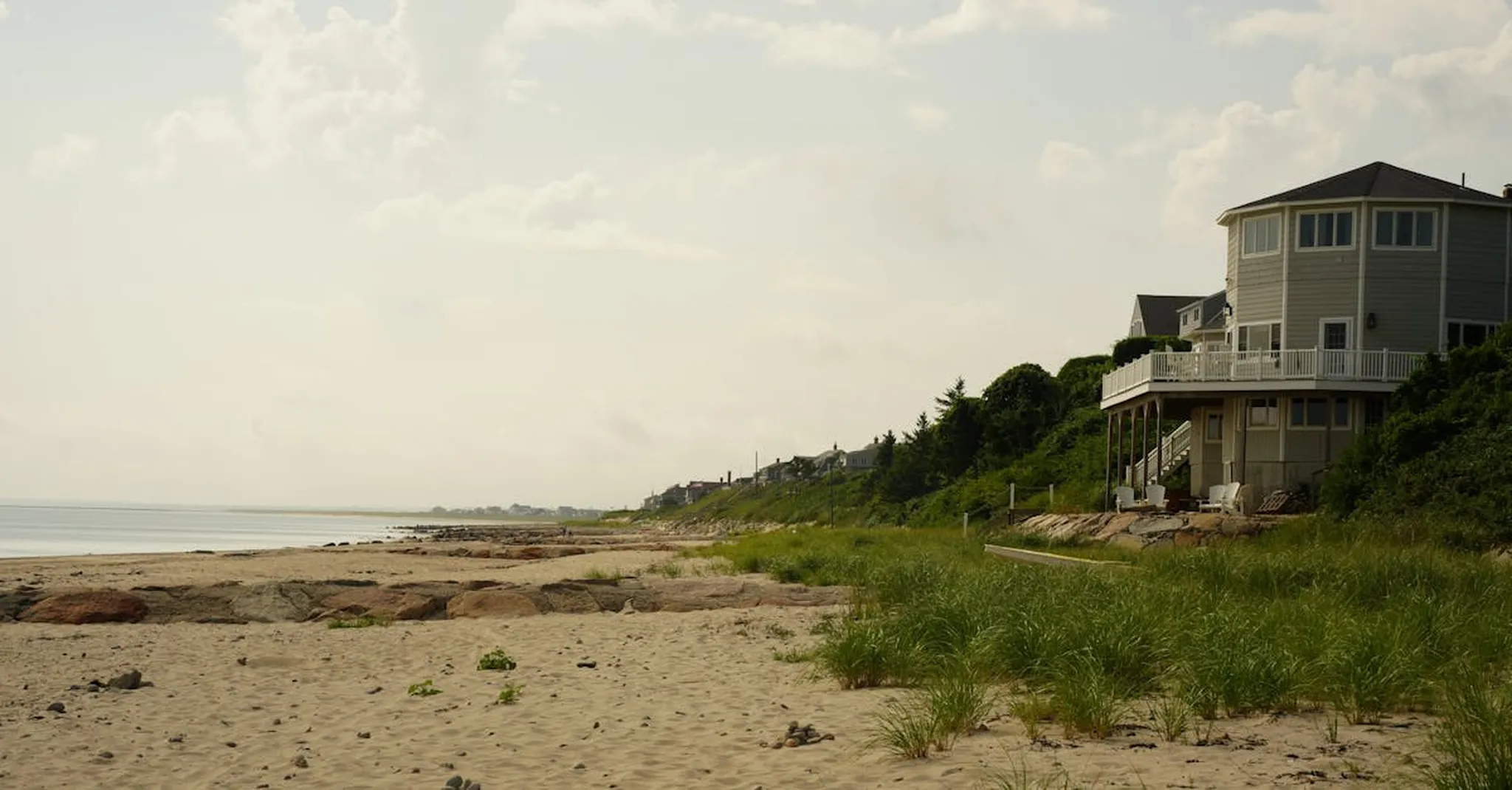 Tranquil sandy beach with coastal house, perfect for summer seaside retreats.