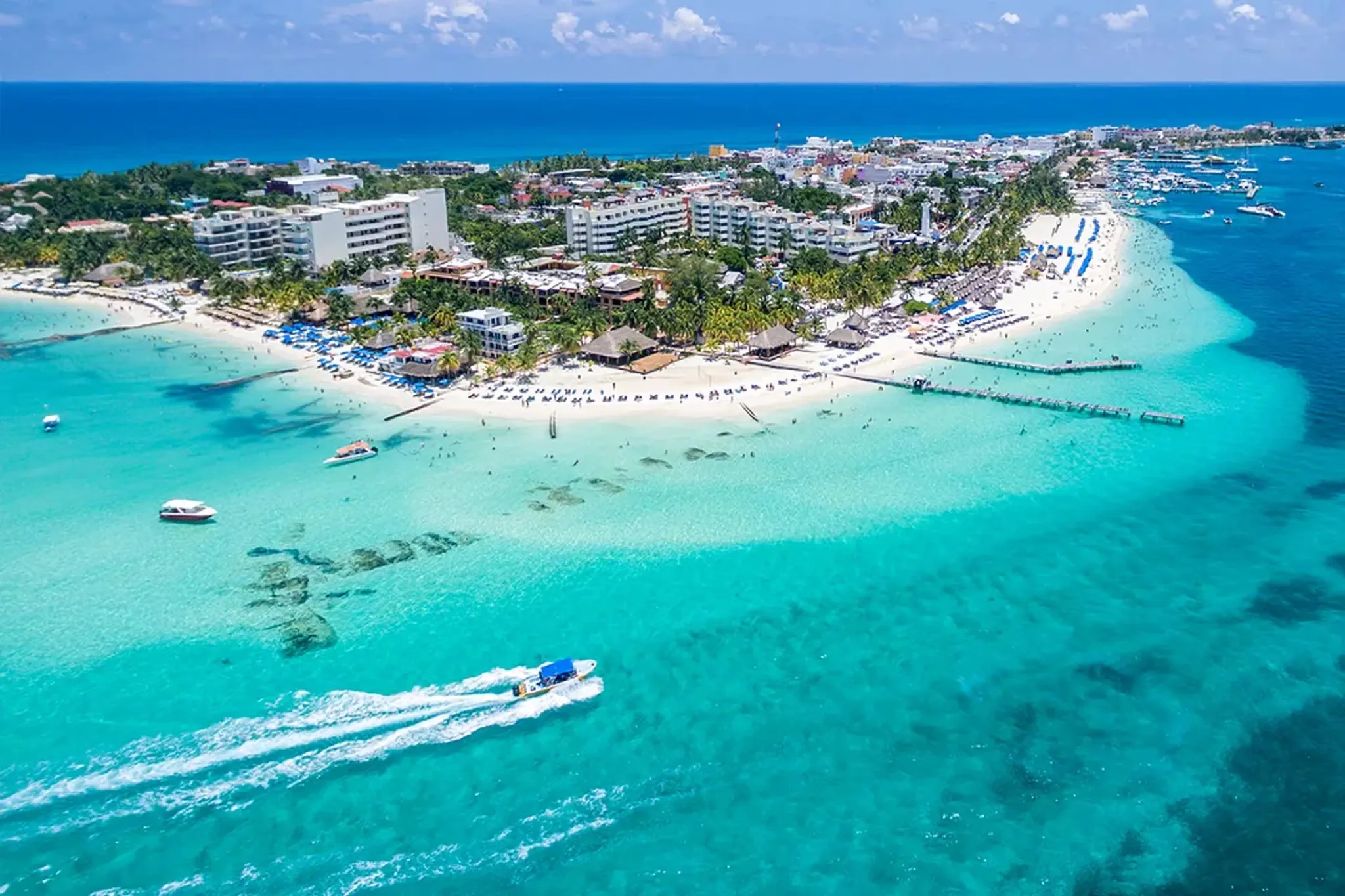 An aerial view of a tropical island beach with white sand and bright turquoise water