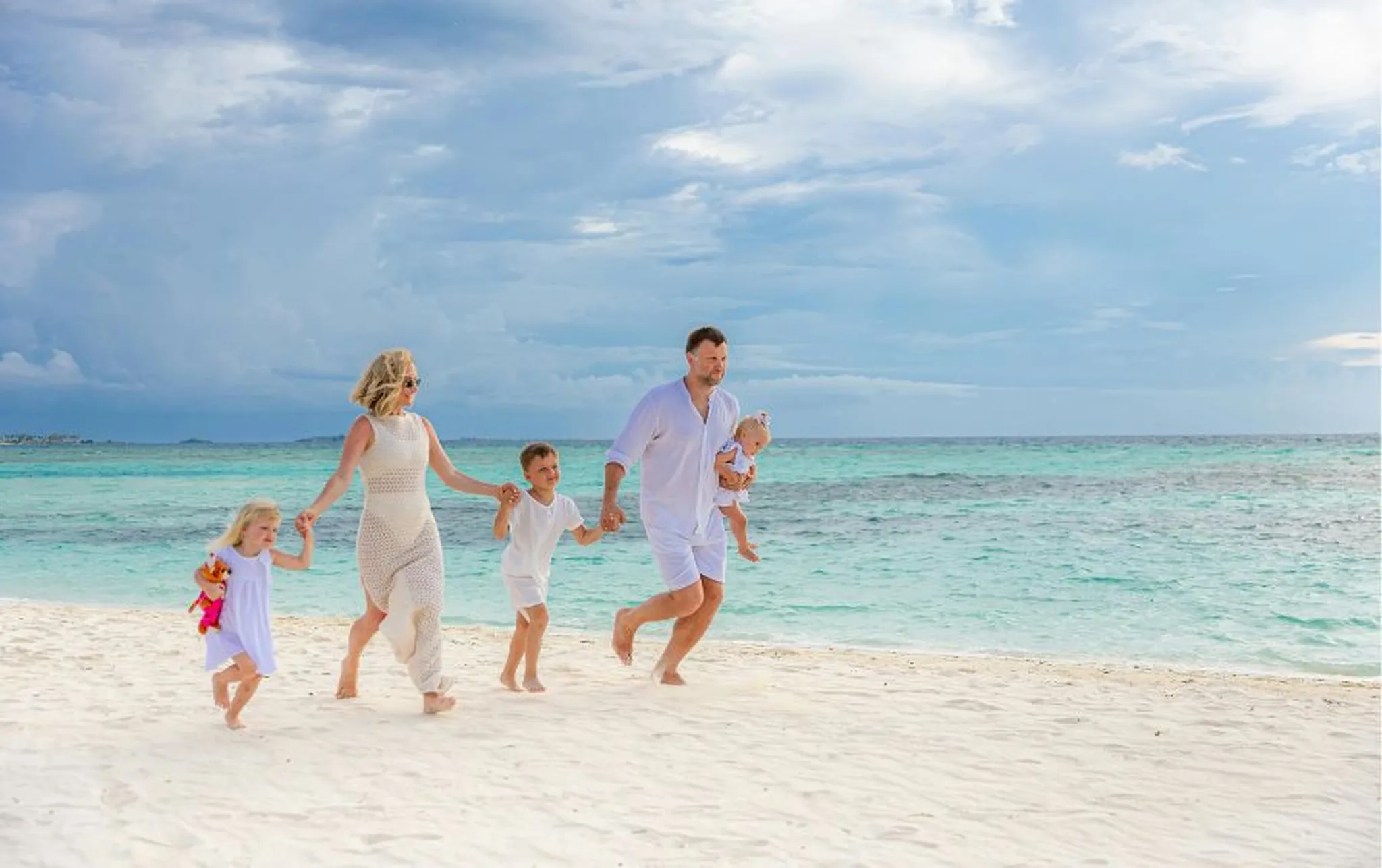A family walking together on a sandy beach next to the ocean