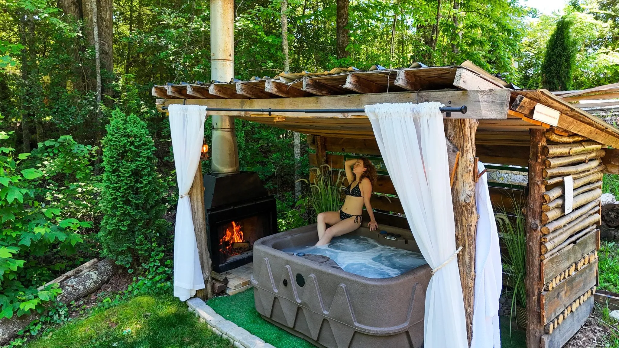Woman sitting on the edge of a hot tub by a fireplace