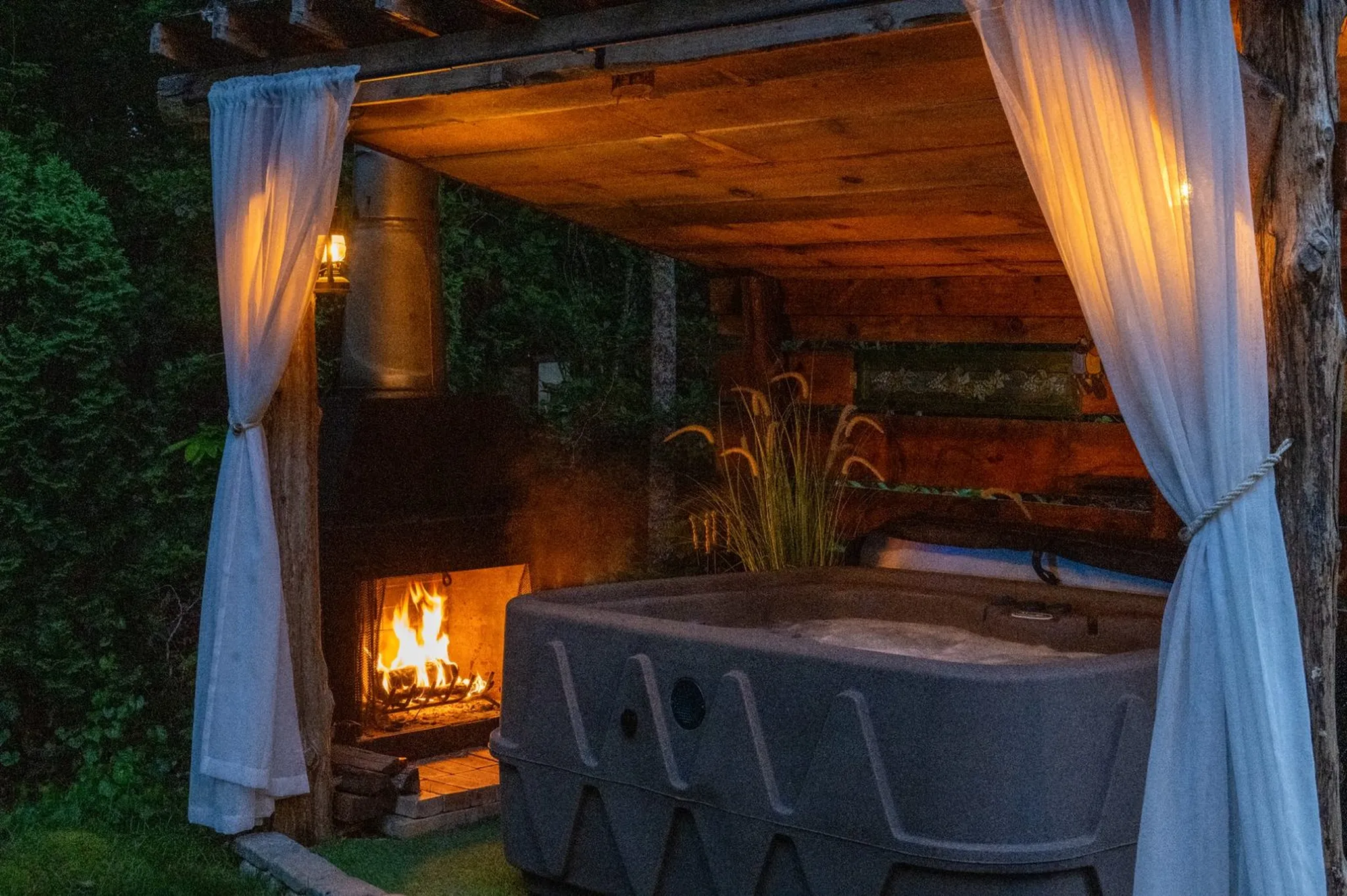 Hot tub under a rustic shack with a wood burning fireplace