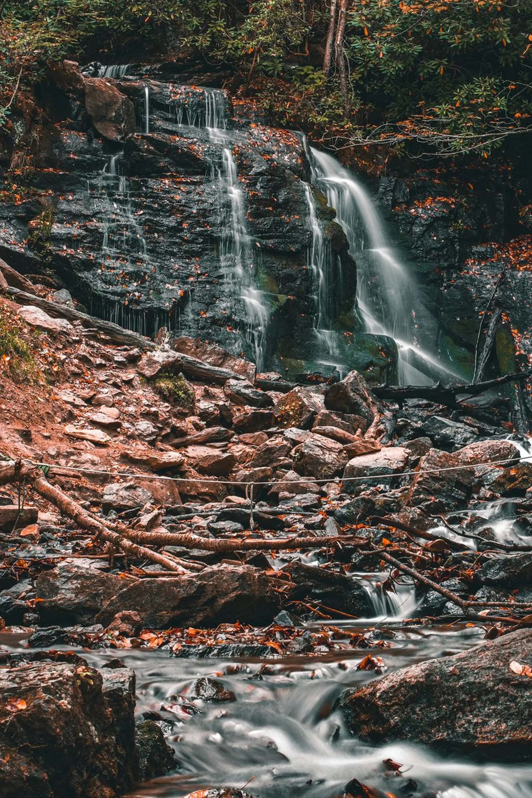 Serene waterfall cascading over rocks in an autumn forest, showcasing nature's beauty.
