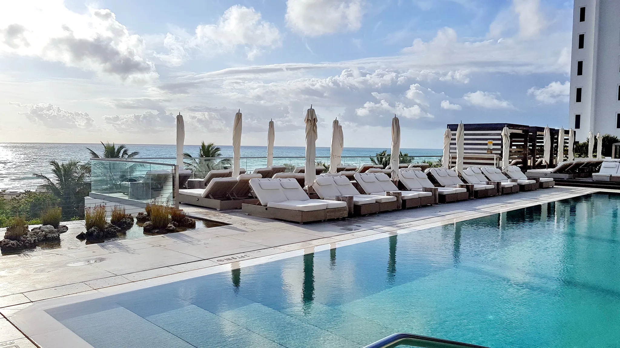 Documentary-style real photograph of Ocean-Facing Pools, Beach Service Included in welcome to south beach luxury vacation rentals, golden hour, photorealistic editorial photography, no people in foreg