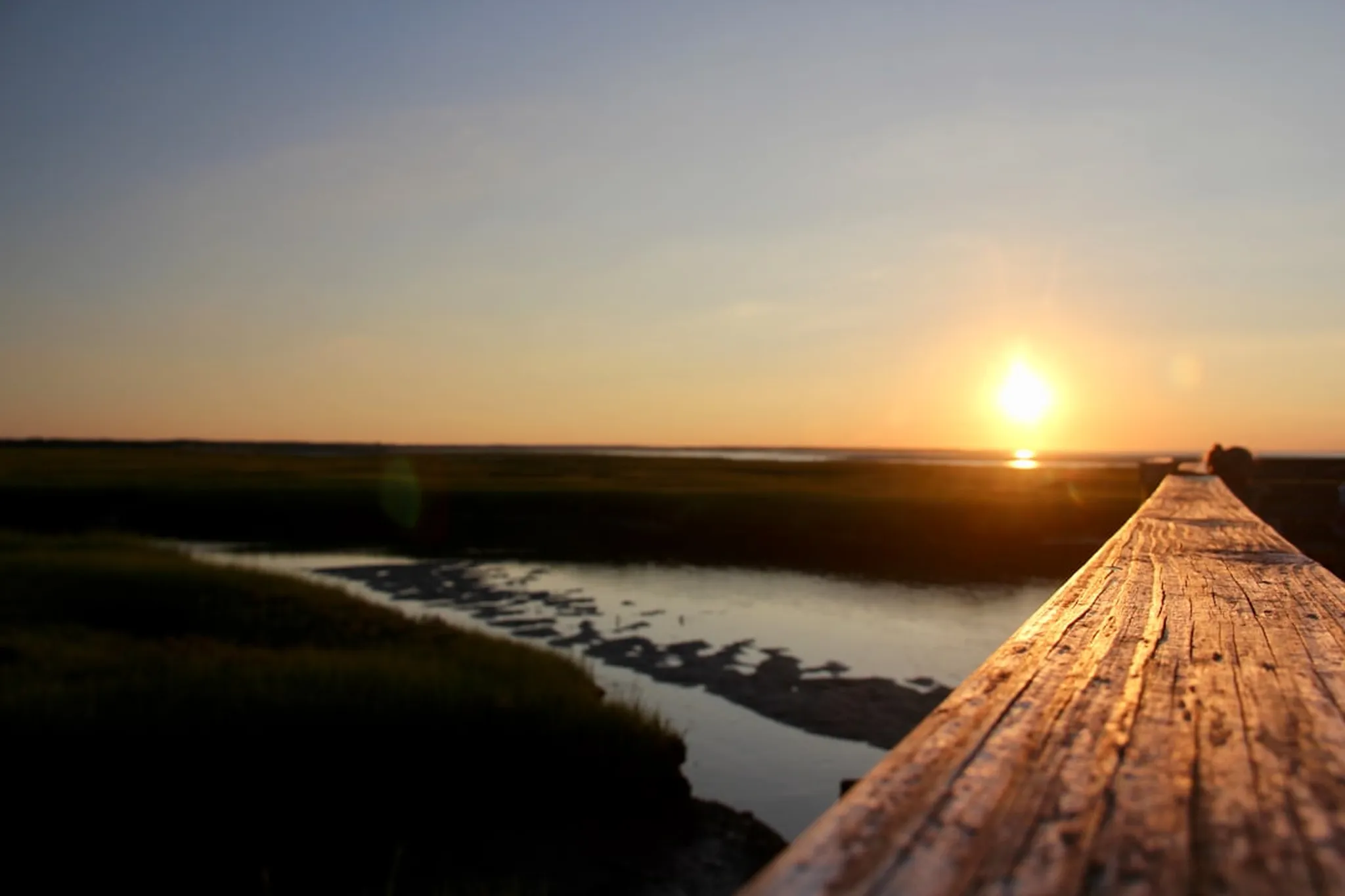 the sun is setting over a wooden pier